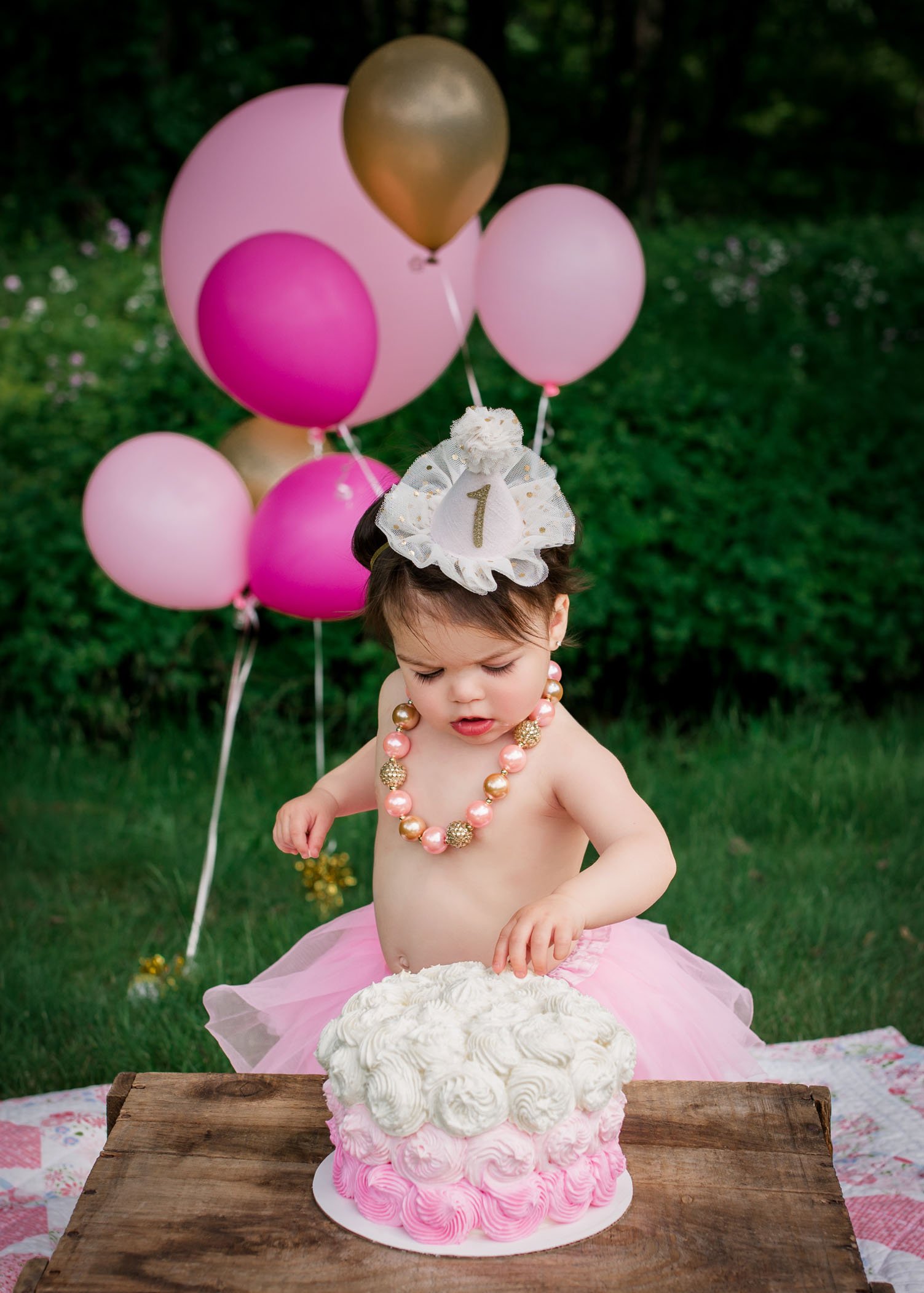 one year old birthday girl touching a cake with her fingers