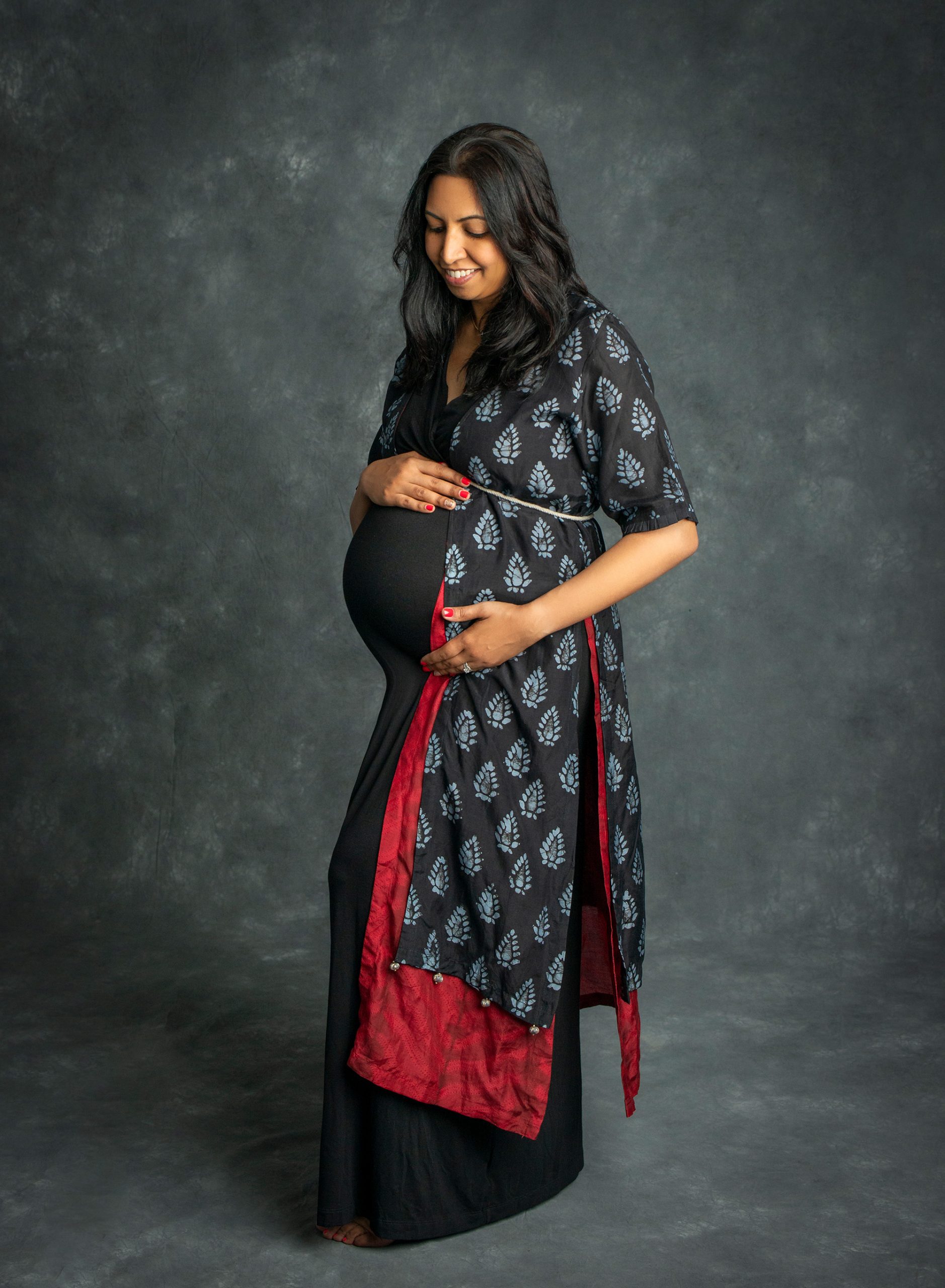 pregnant woman holding stomach posing in black dress