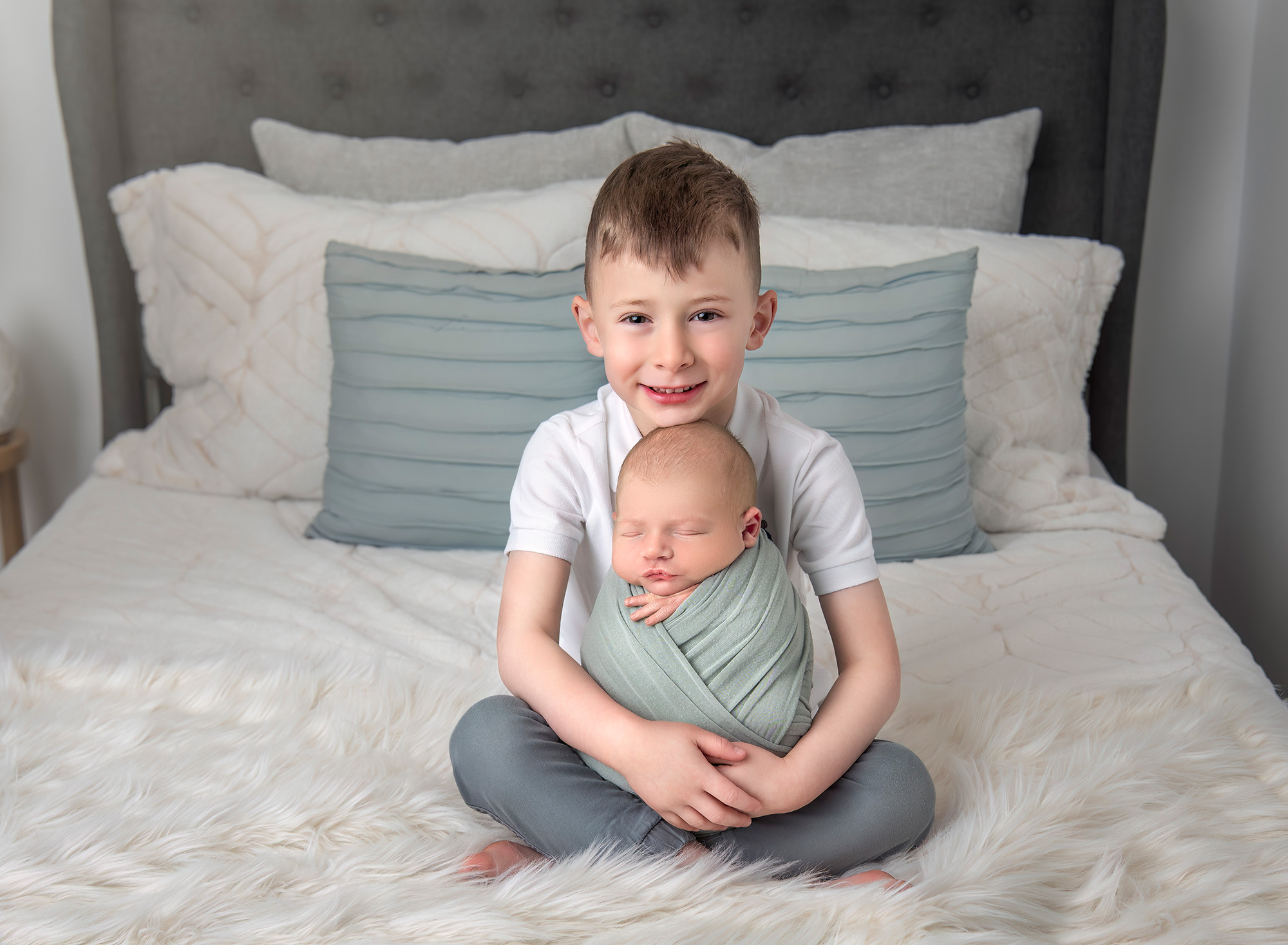 Family Photography with Newborn Evan sitting cross-legged with Owen swaddled in his lap