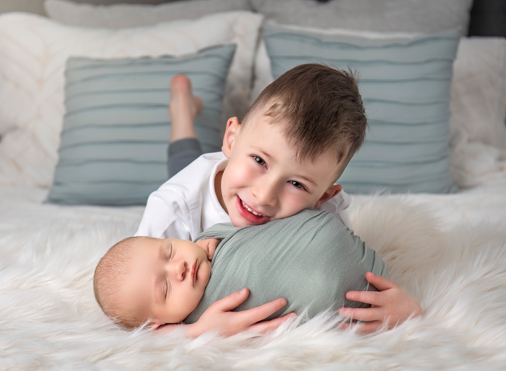 Big brother Evan cradling Owen on the bed