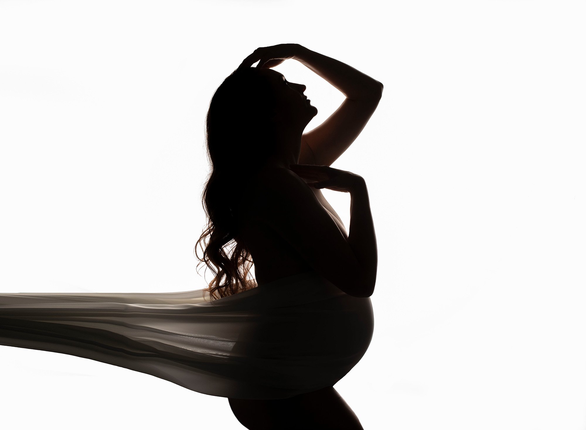 shadow of a pregnant woman on a white background wearing a flowy dress