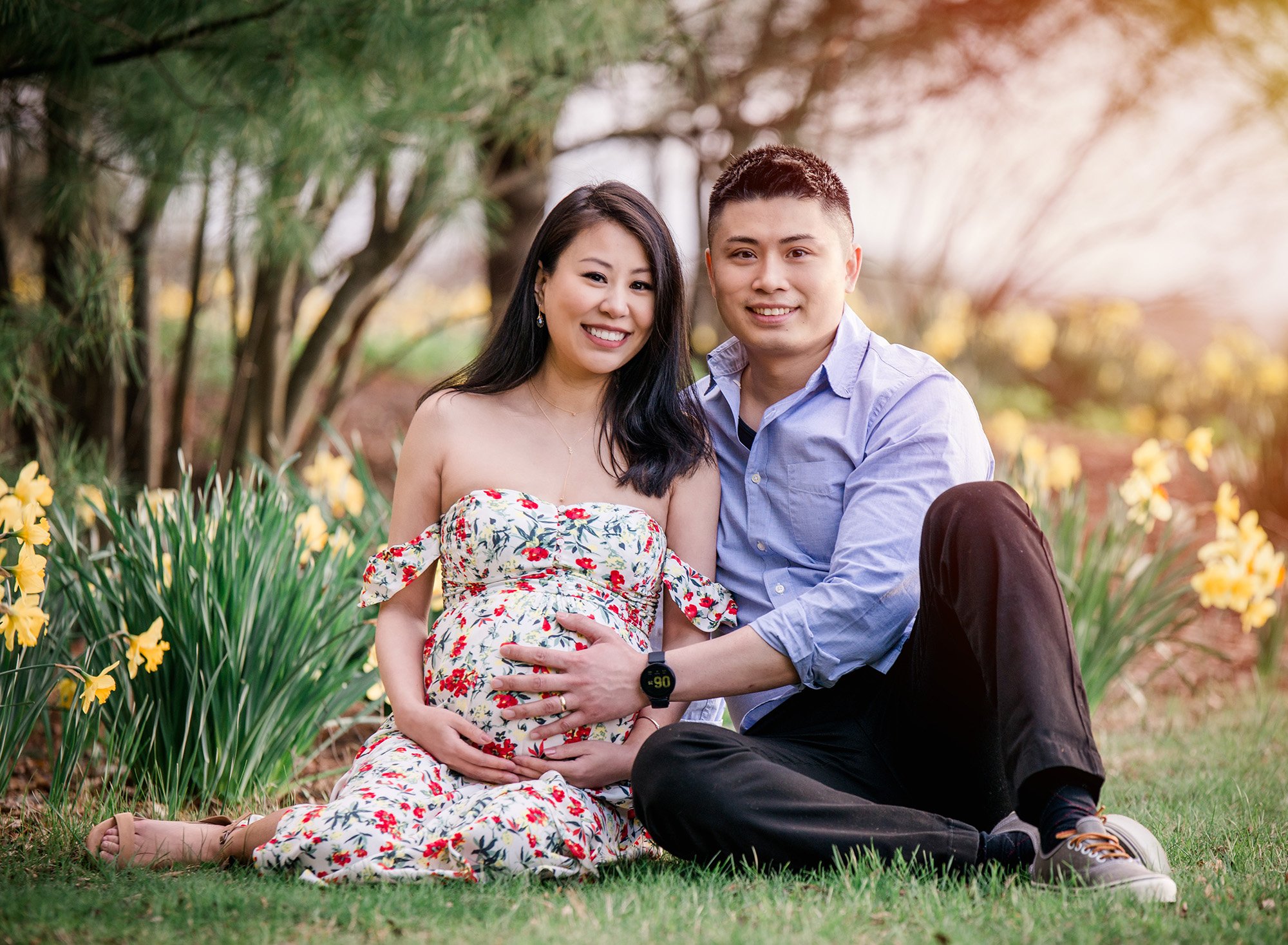 garden flower maternity photos pregnant woman in floral maternity dress sitting outside with partner