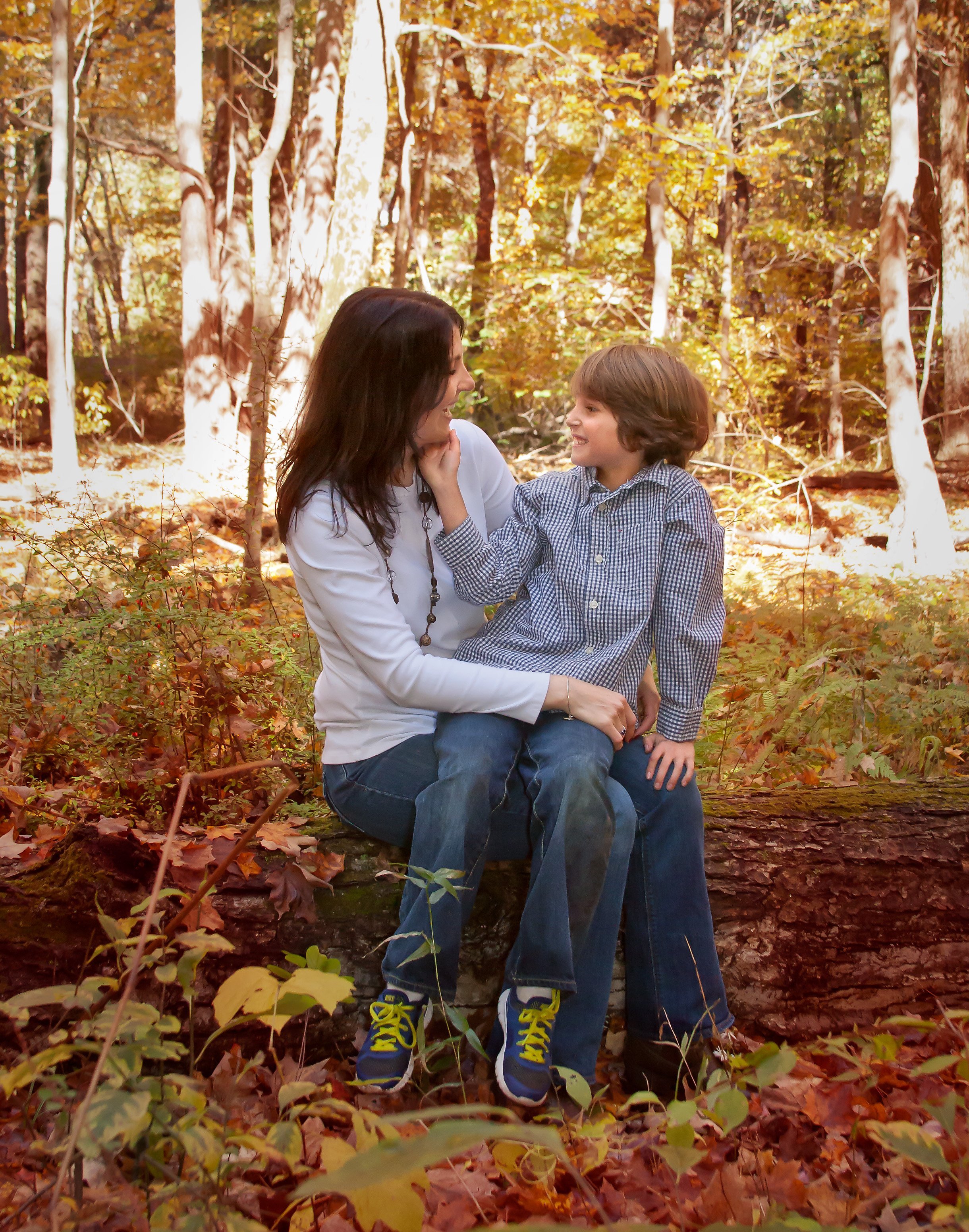 Mom and young son talking in the woods sitting down