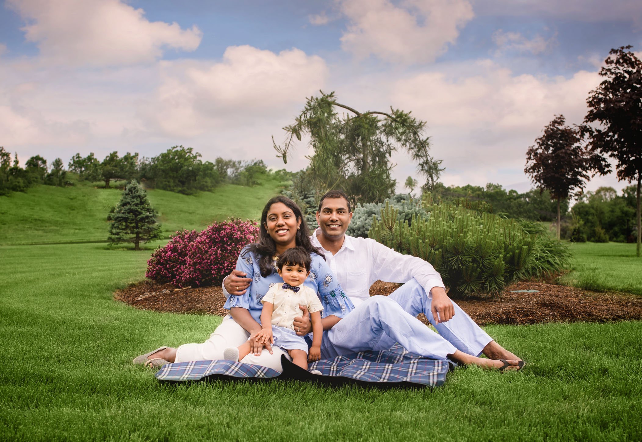 Indian family of 3 sitting on blanket in the garden