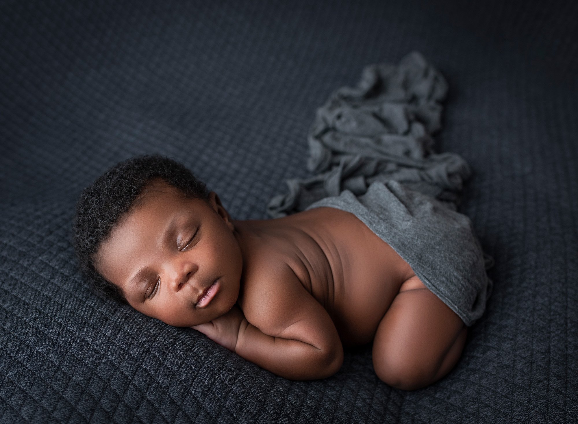 newborn baby boy asleep with draped grey blanket over bottom