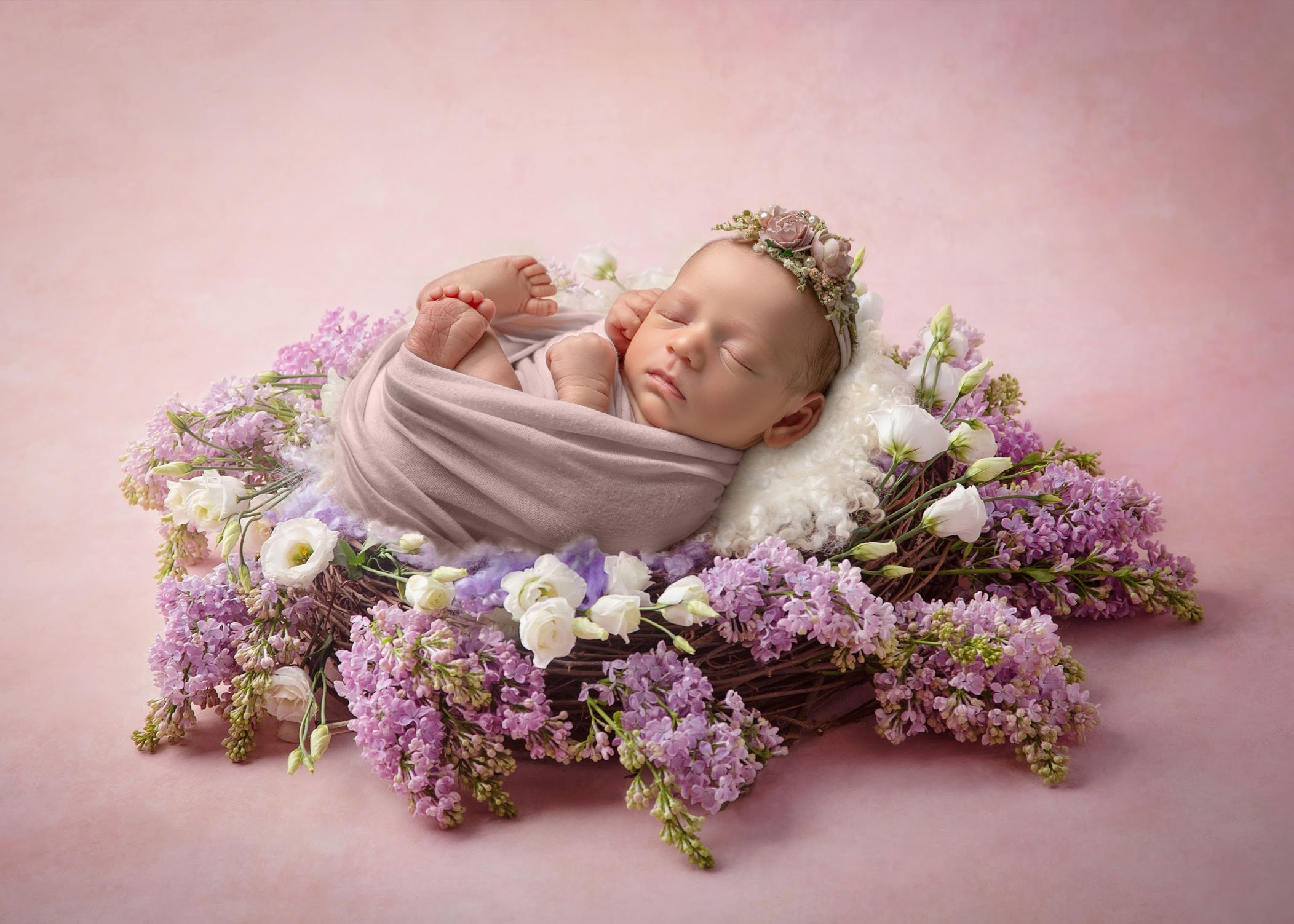 baby girl sleeping in a nest of spring flowers