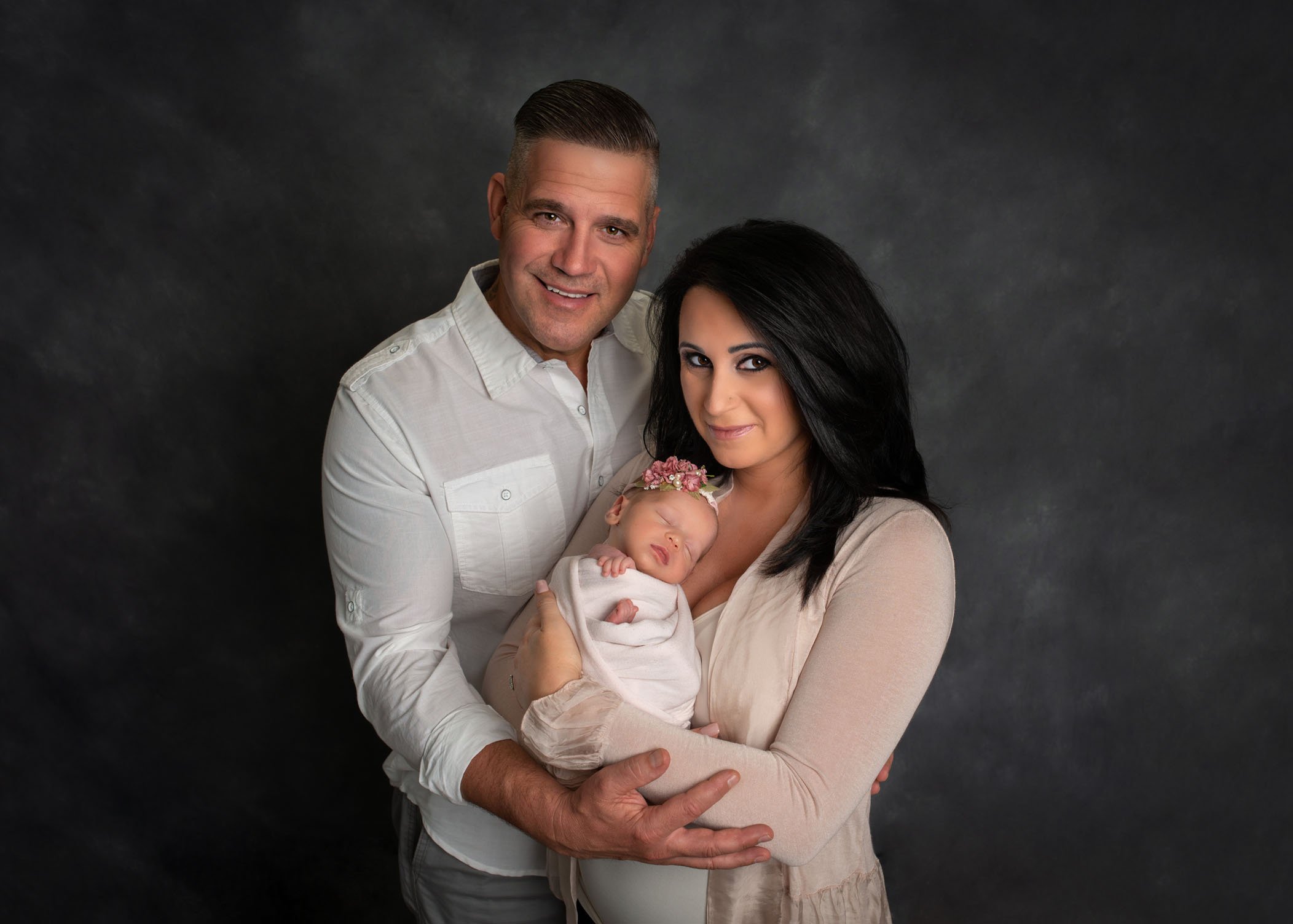 Mom Dad and newborn baby pose for first family portrait