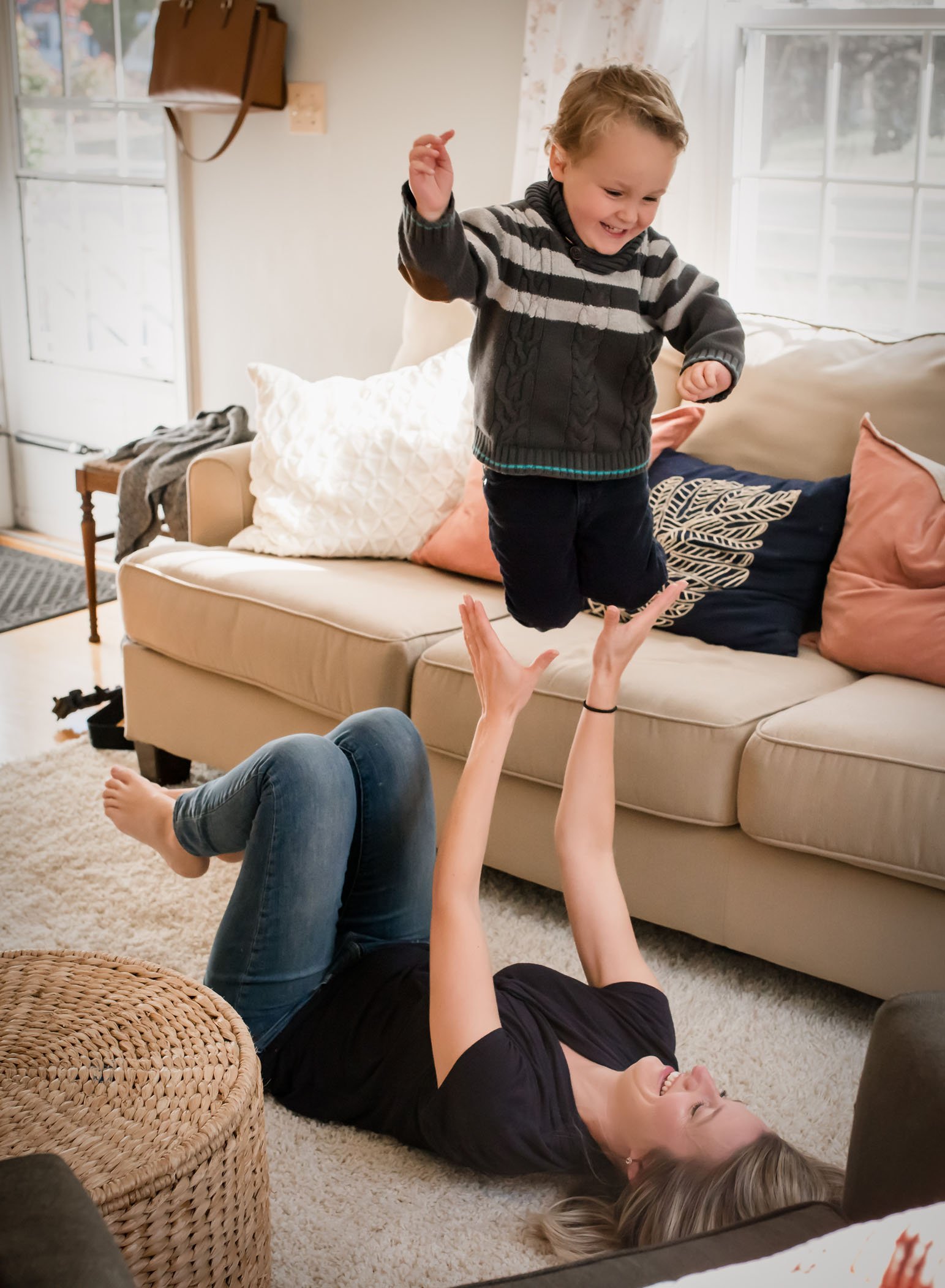 4 year old boy jumping off couch into mom's waiting arms