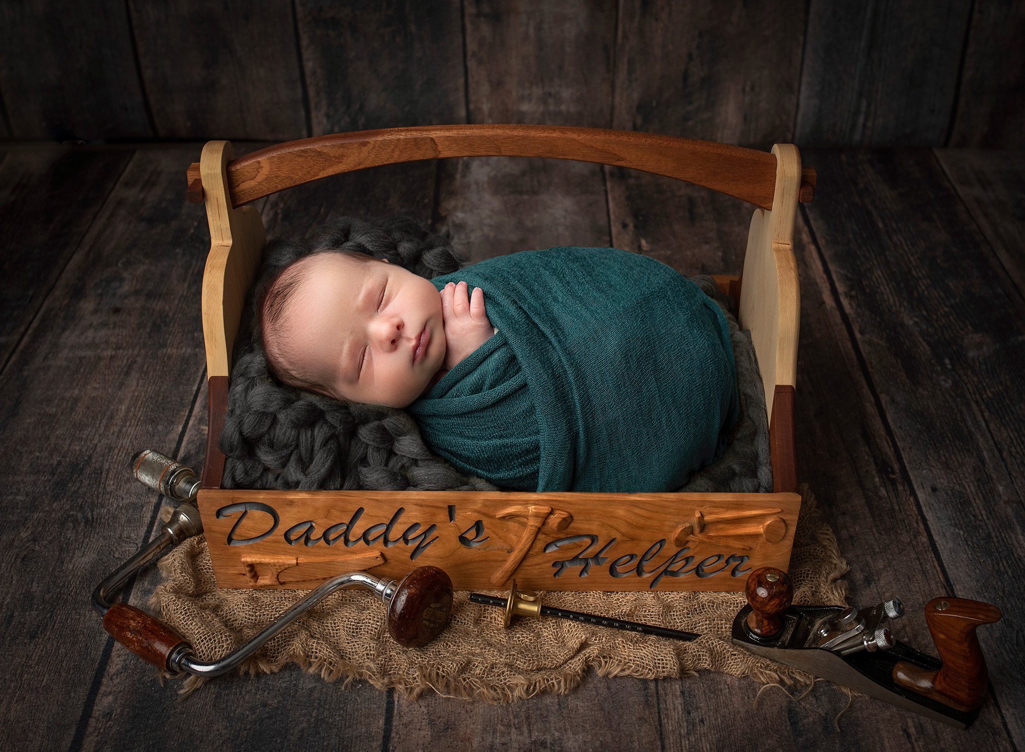 newborn baby boy swaddled in teal asleep in a "Daddy's Helper" welded crate