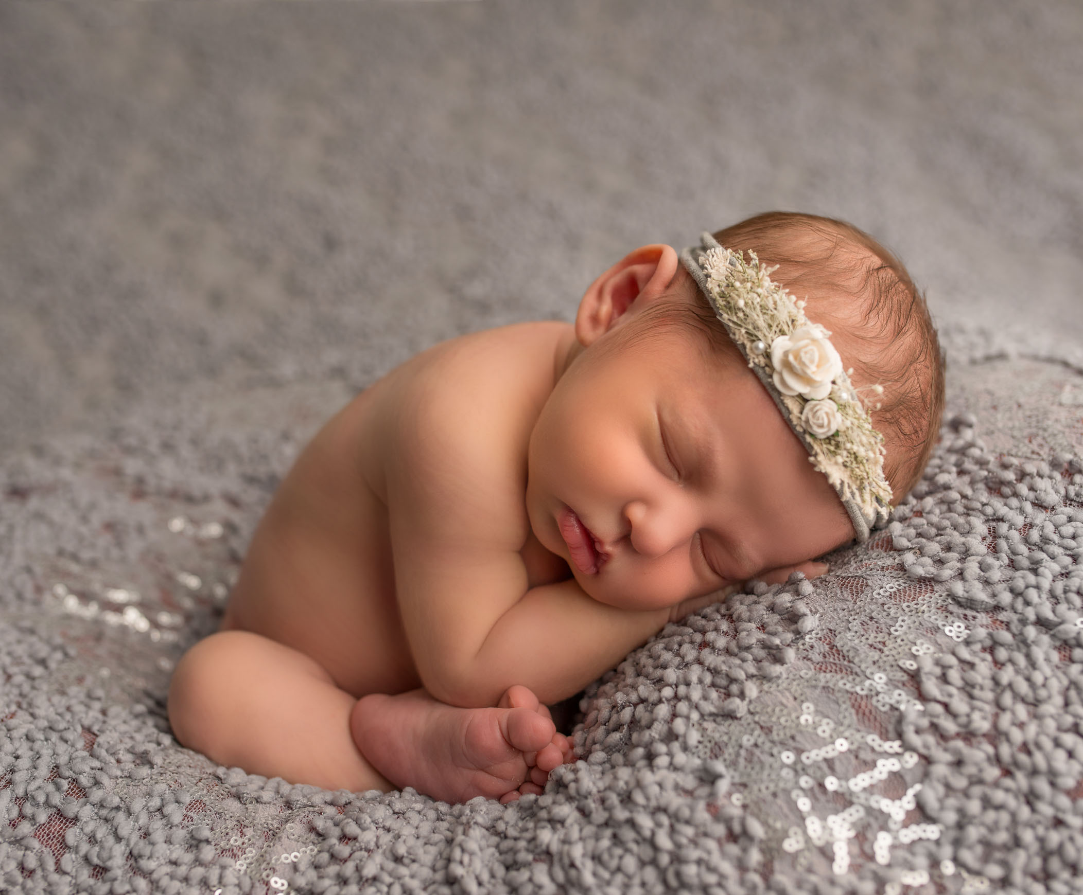 newborn baby girl in womb pose with headband