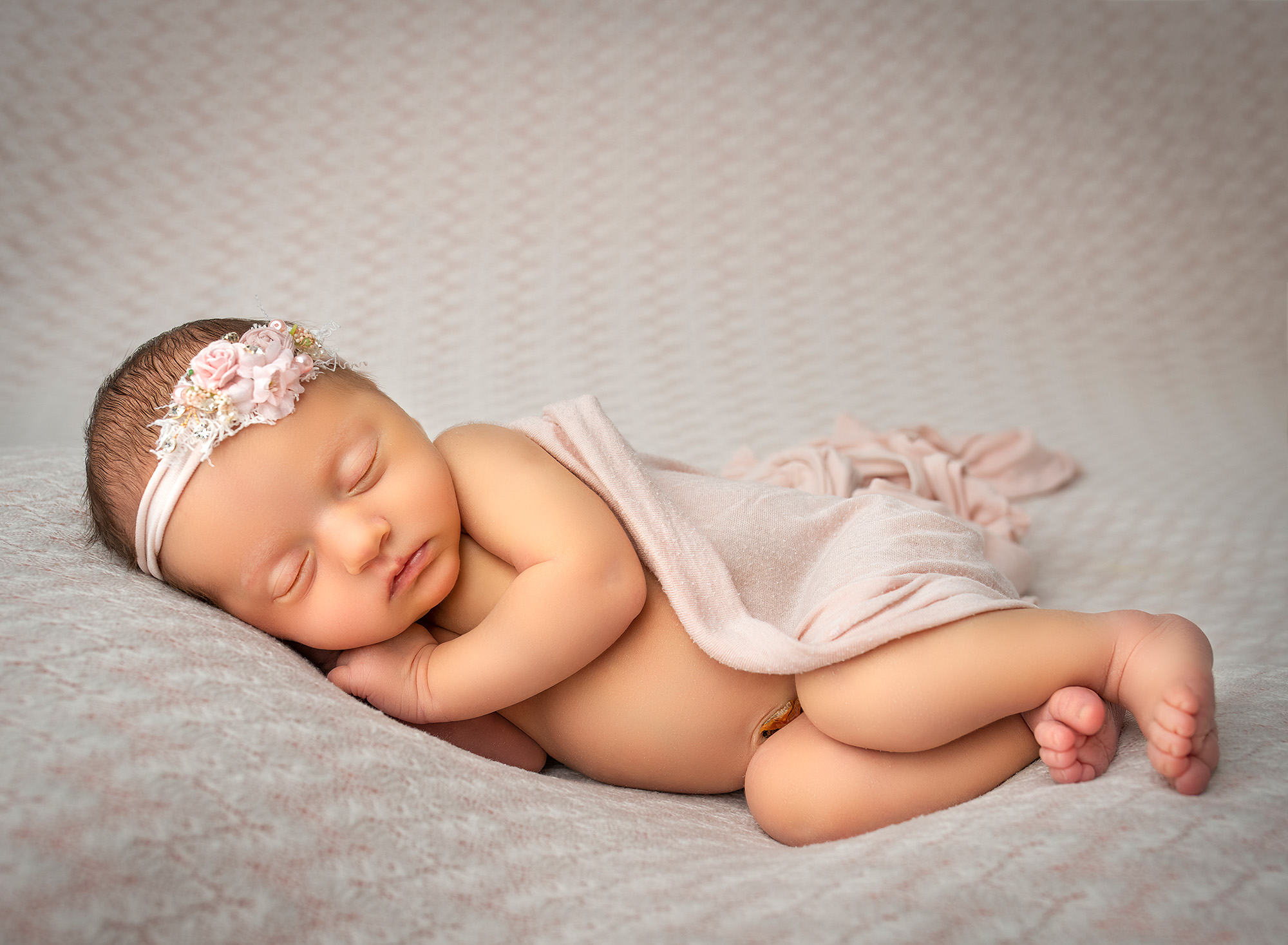 Newborn Family Photographer A simple yet heartwarming scene of a baby sleeping with a pink blanket, evoking warmth and tenderness