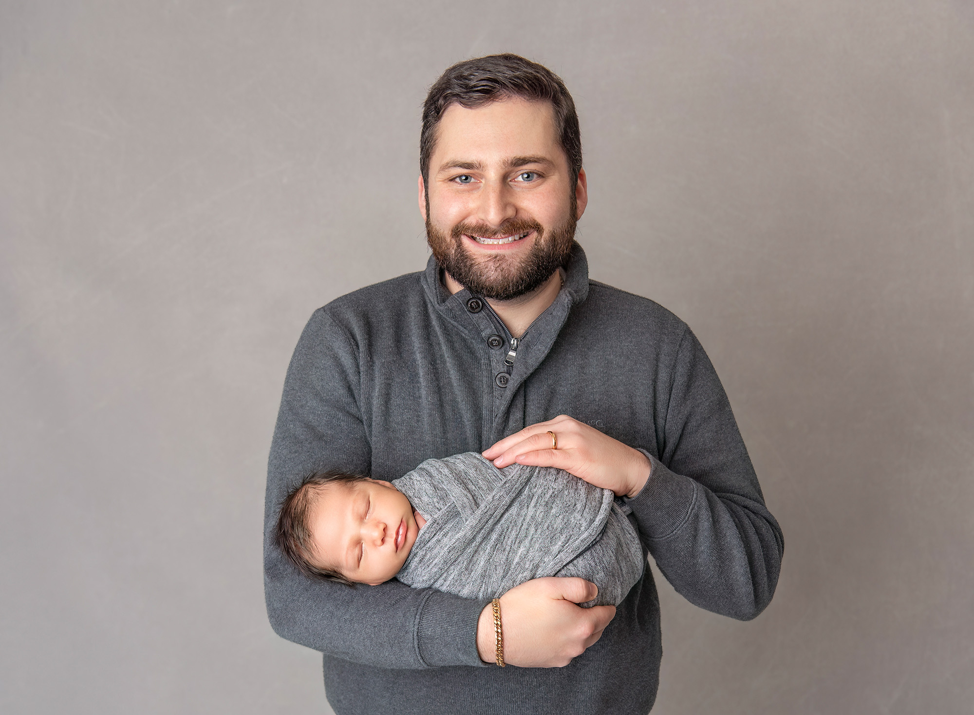 Dad smiling cradling his newborn son