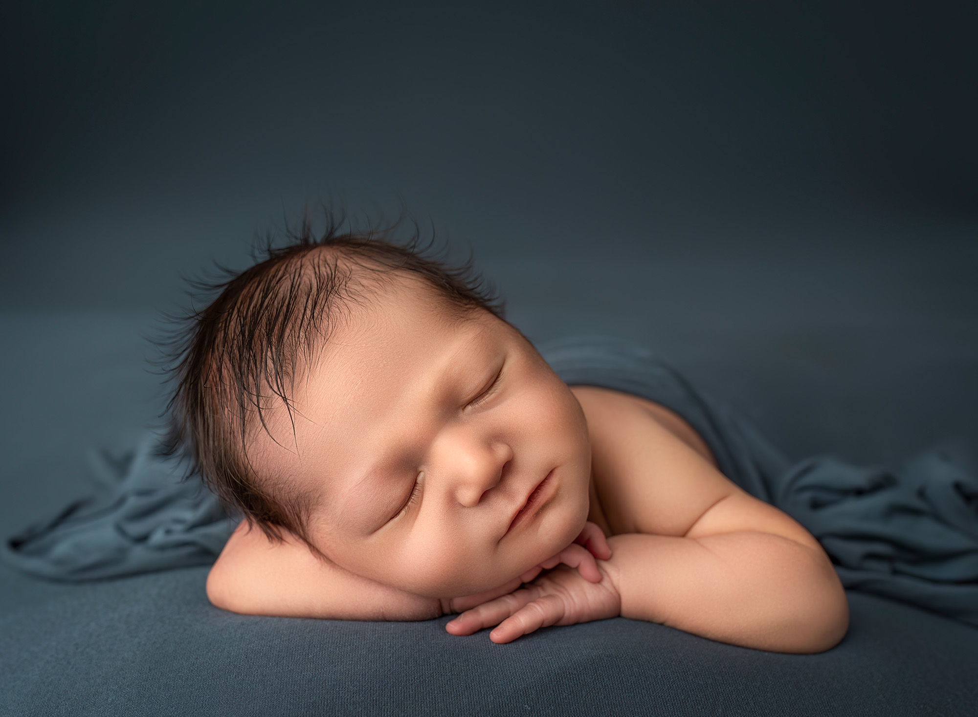 Newborn baby boy sleeping with head on hands