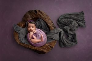 Newborn Girl Photography newborn baby girl sleep in purple swaddle inside of wooden heart