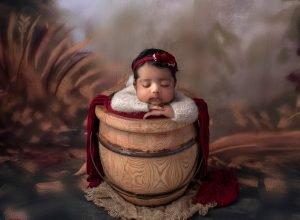 Newborn Girl Photography newborn baby girl asleep in honey pot wearing red headband