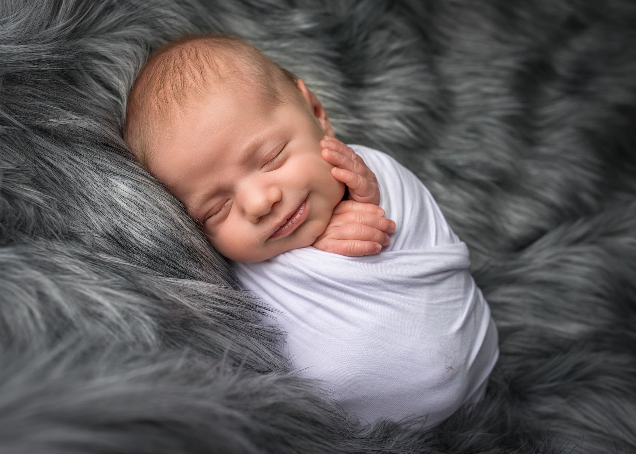 sleeping swaddled newborn smiling on his side