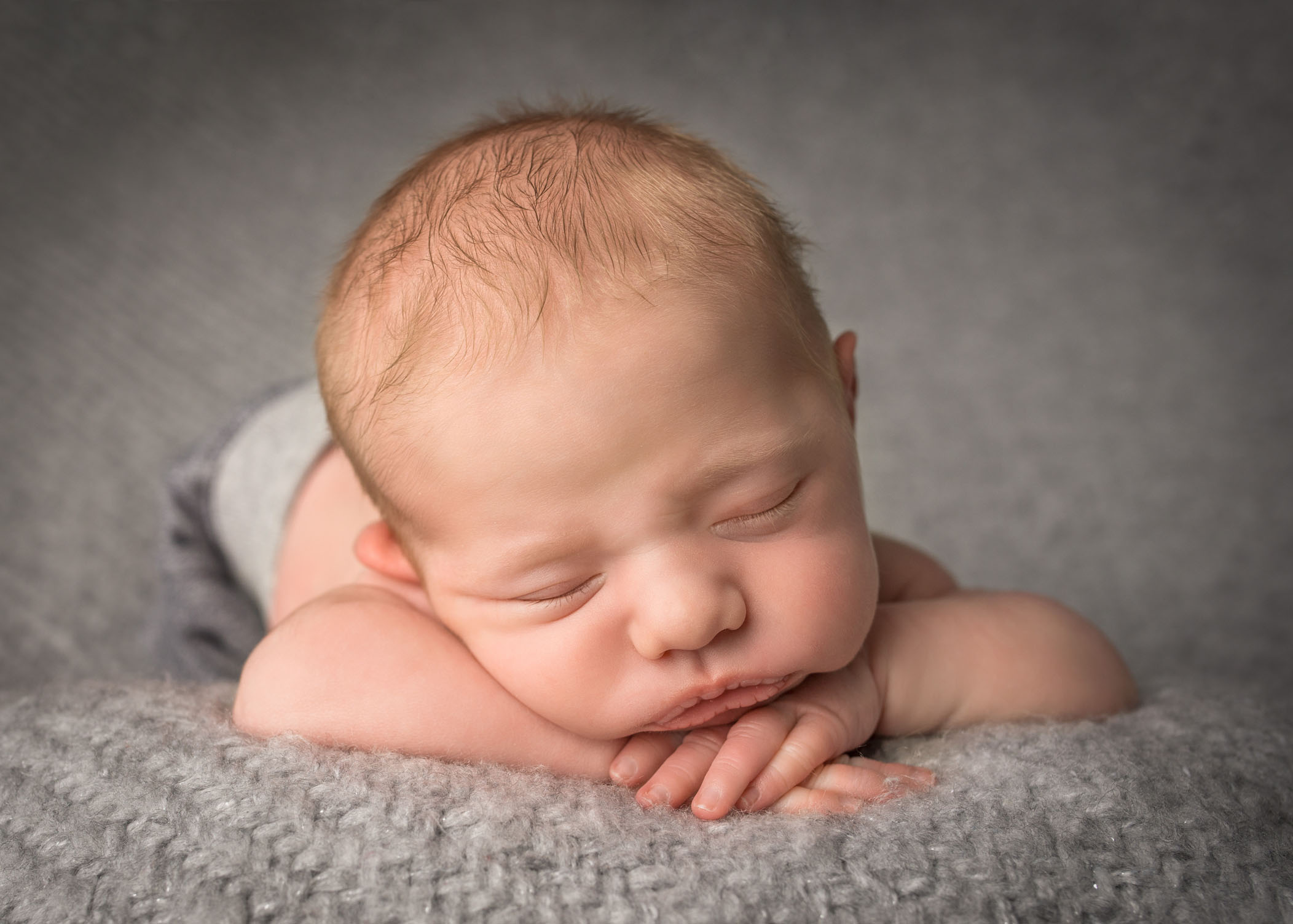 newborn baby boy asleep with head resting on his hands