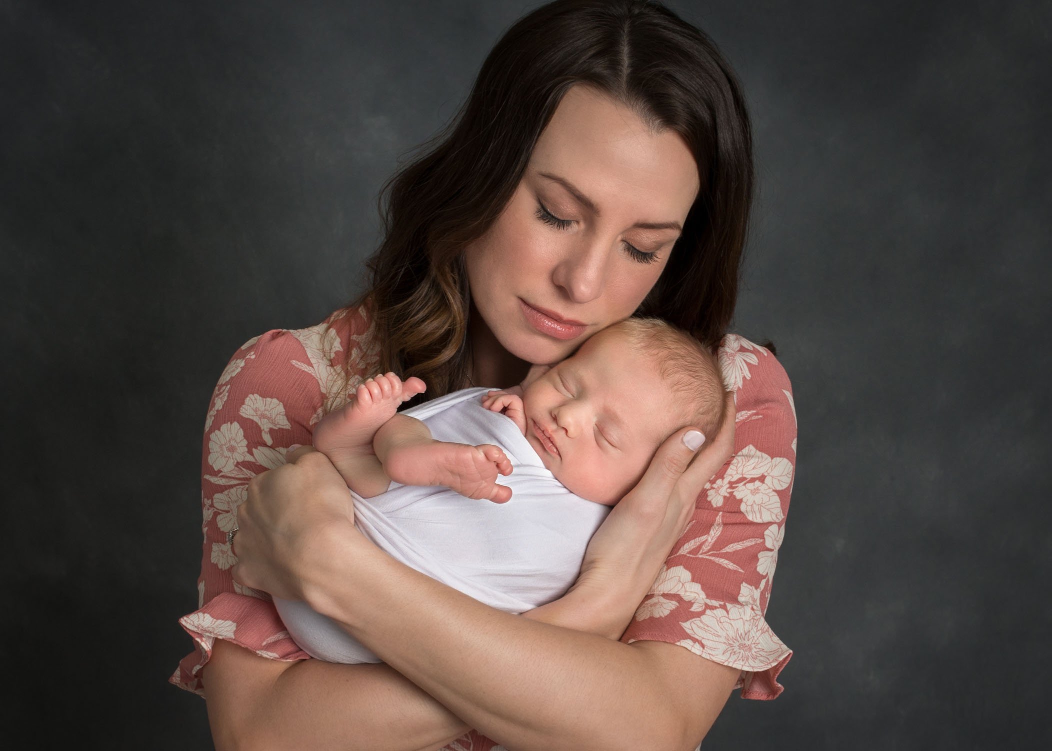 Mom holding swaddled newborn in her arms