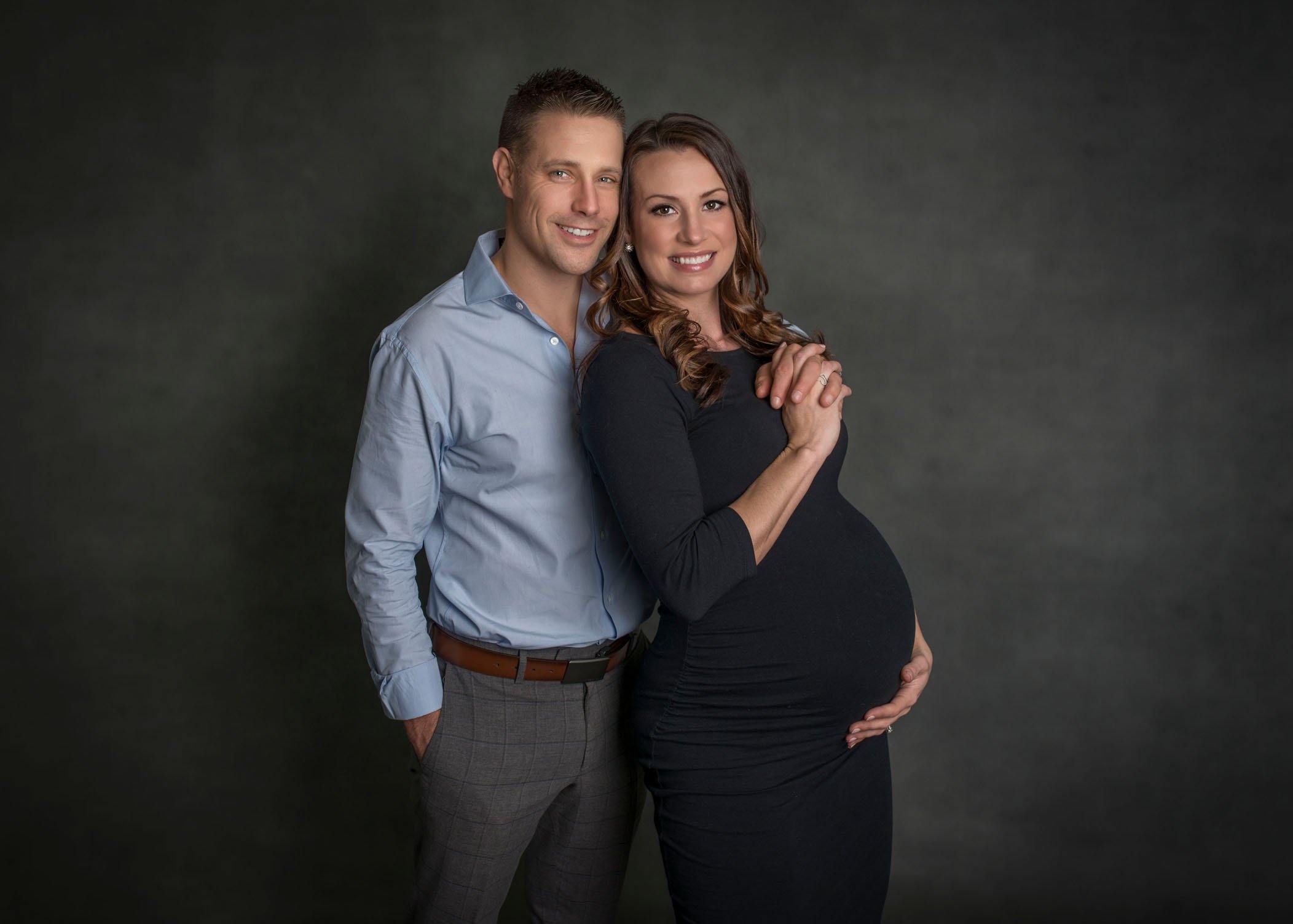 Pregnant mom and dad to be posing and smiling at studio