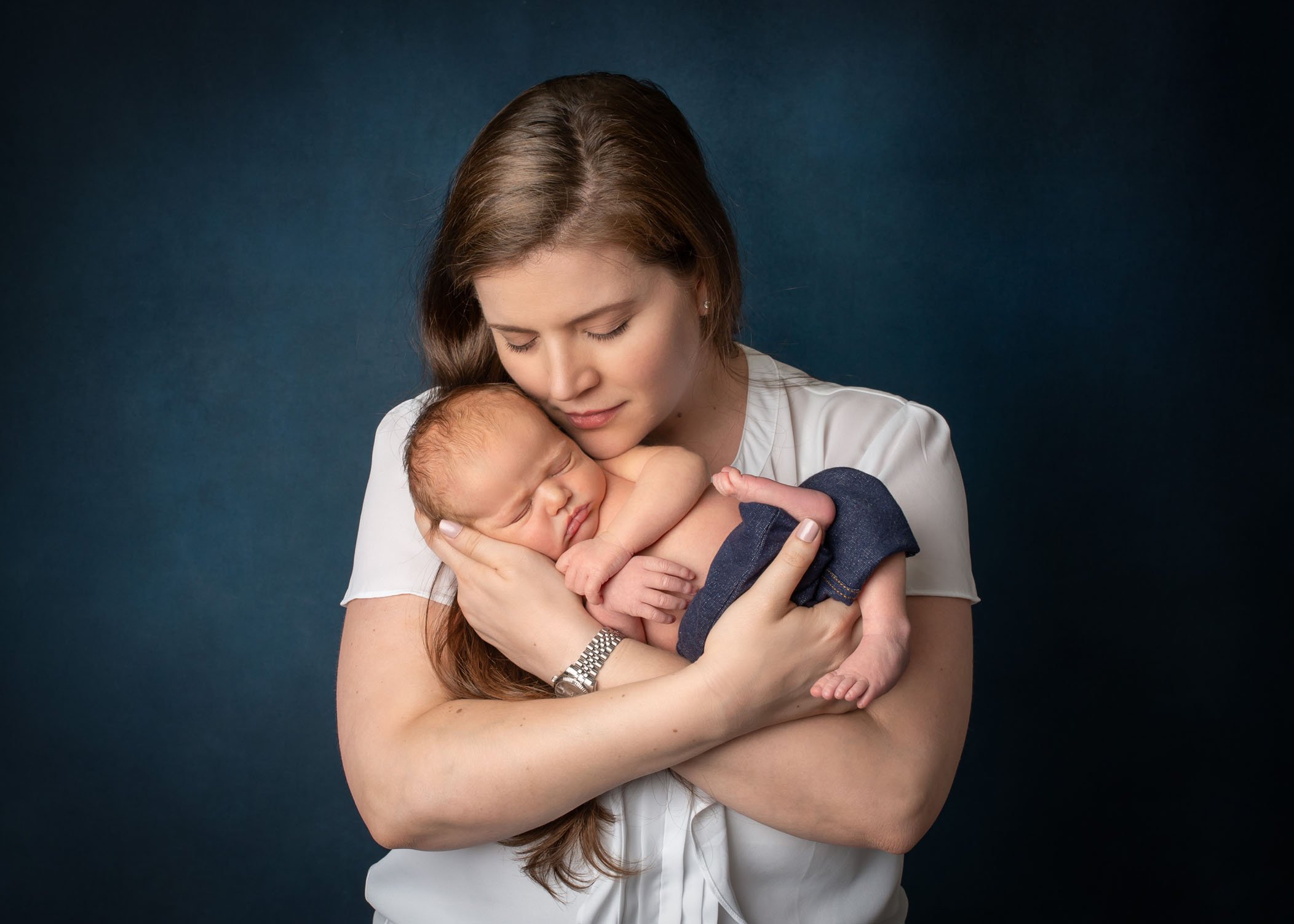 Mom cradles her newborn son in her arms with her eyes closed