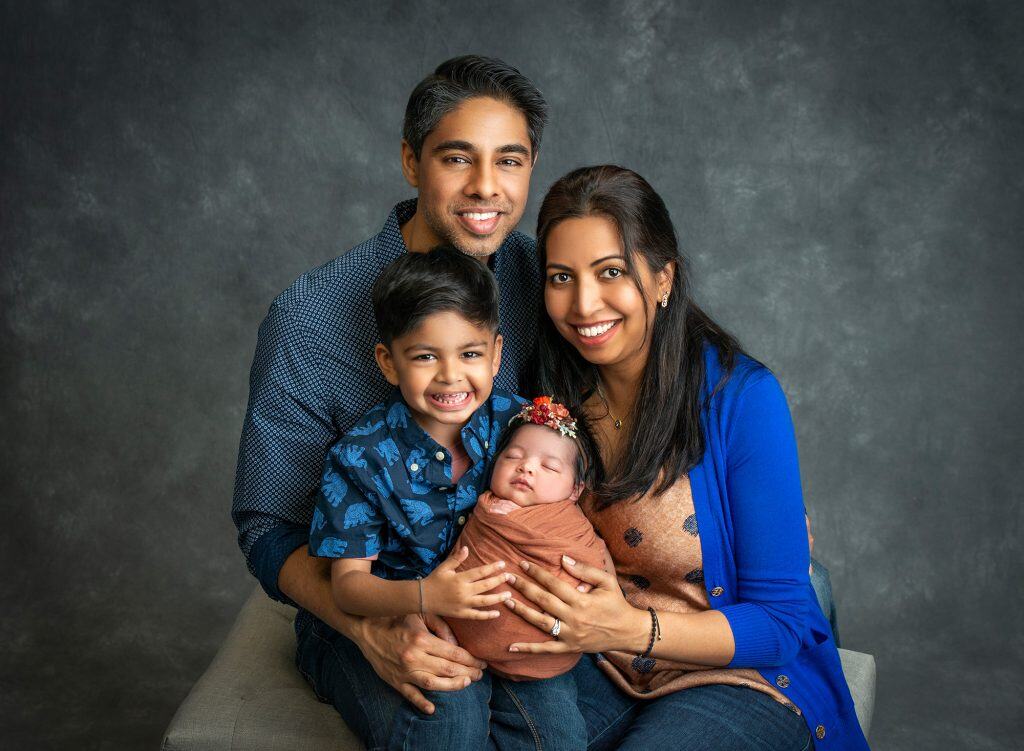 Meaningful Newborn Photos couple posing with young son and newborn baby girl swaddled in rustic orange