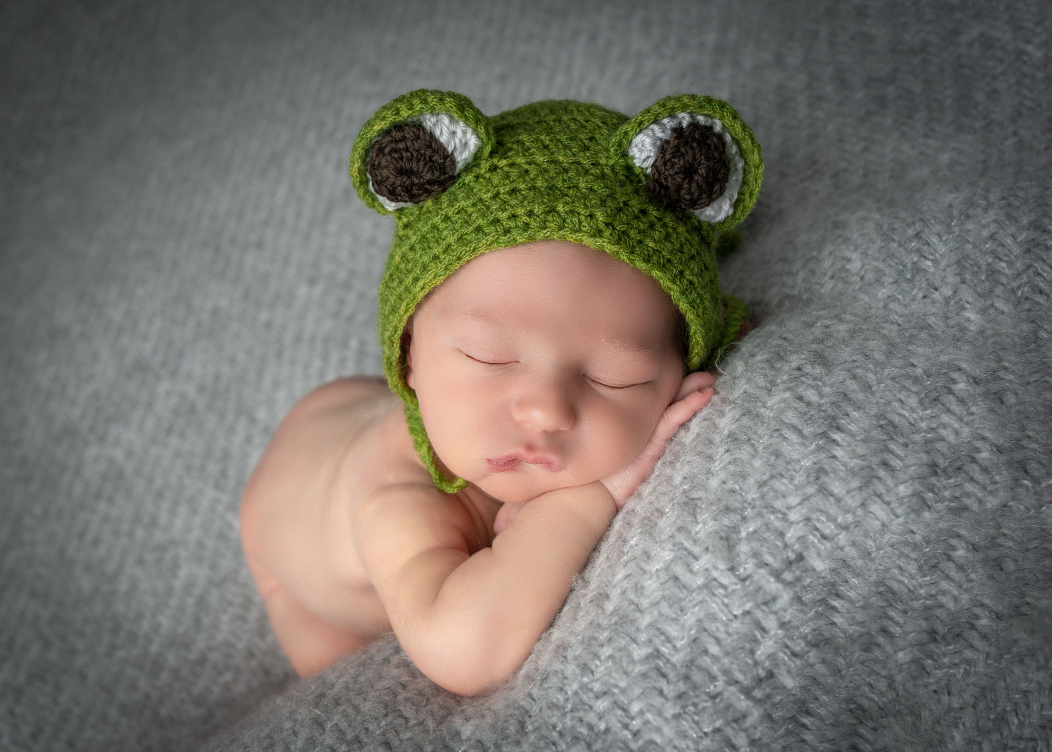 Newborn boy sleeping with knitted froggy hat on