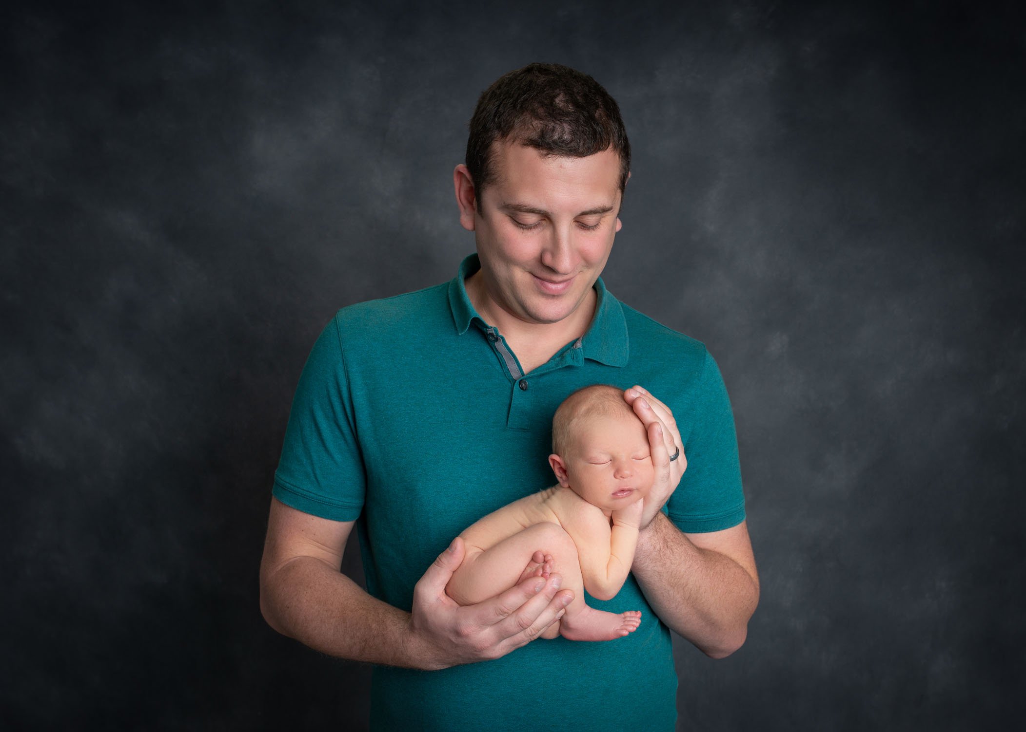 Dad holding newborn son in palms of his hands