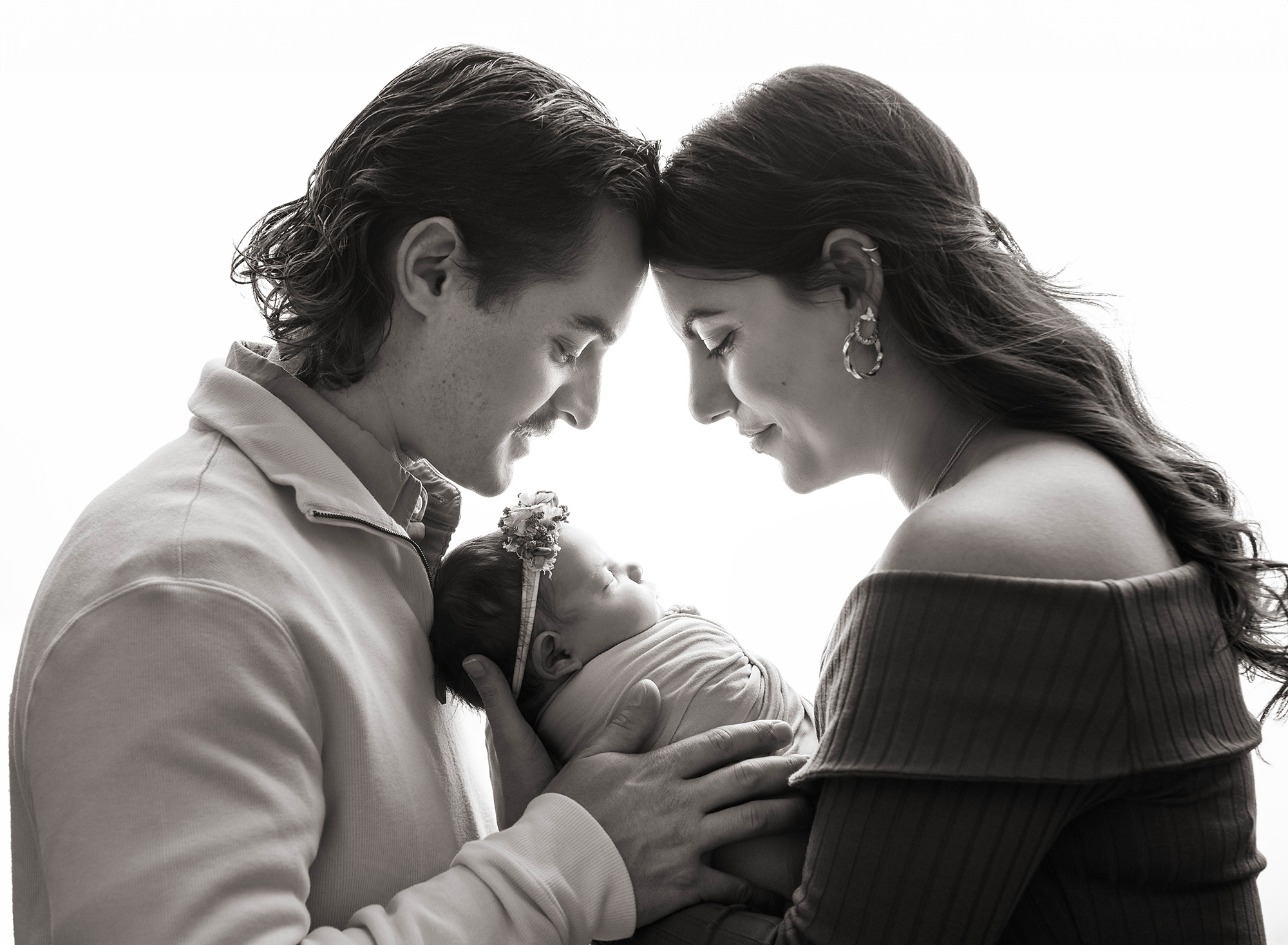 Newborn Studio Photography Black and white portrait of parents looking down at newborn baby girl