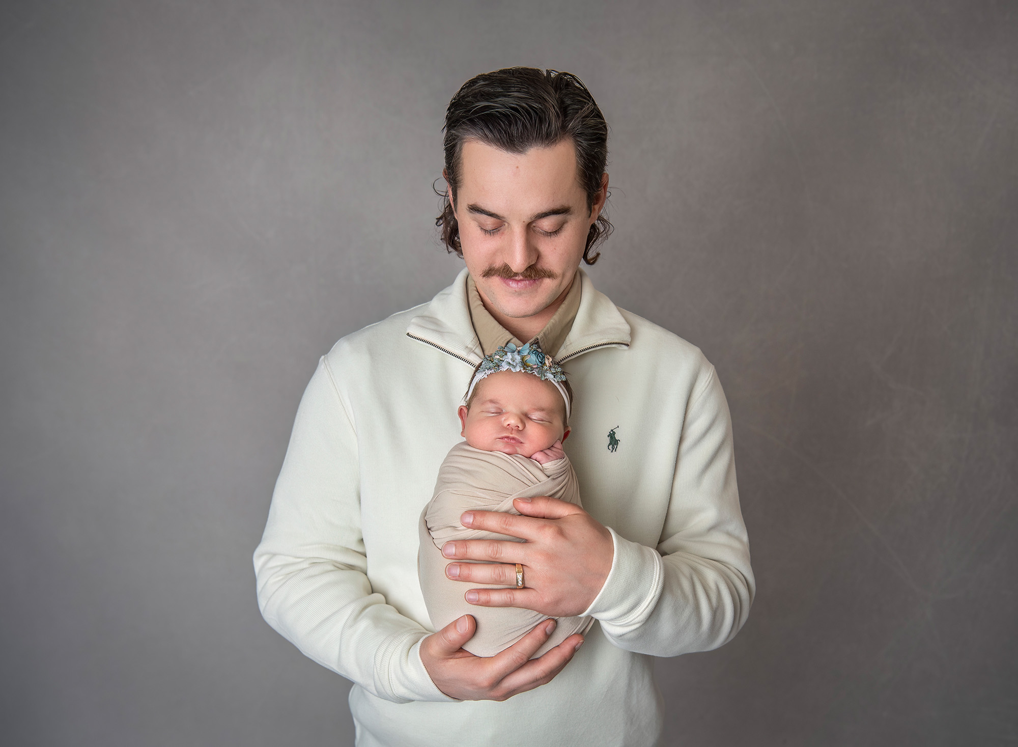 Dad cradling newborn baby girl looking down at her