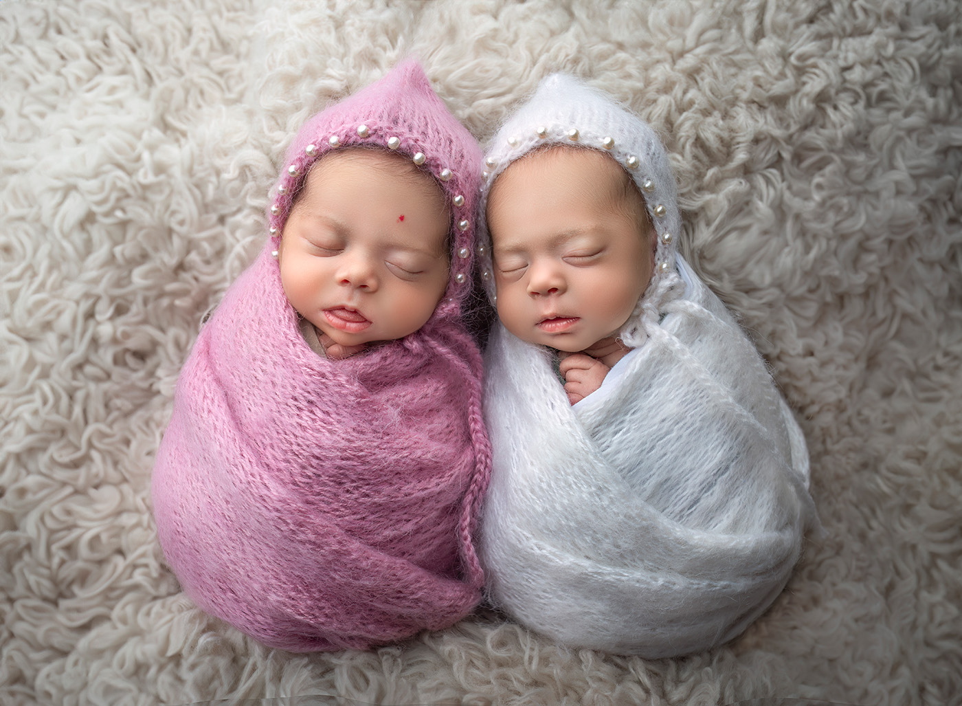 newborn twin photography newborn girls swaddled in pink and white with pearls surrounding their faces