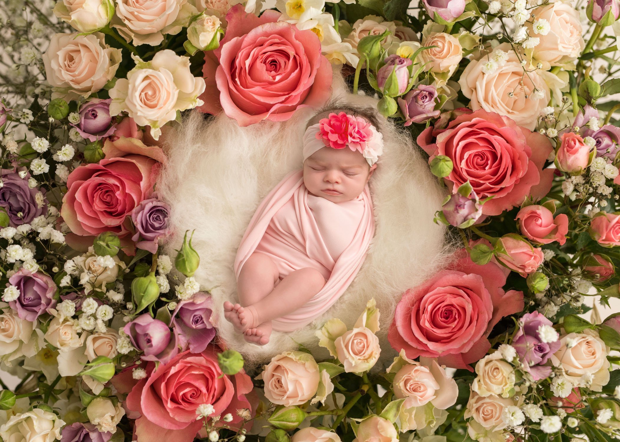 newborn baby girl sleeping in bed of roses