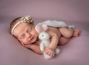 newborn sleeping with a wool mouse with a pink background best time to take newborn photos