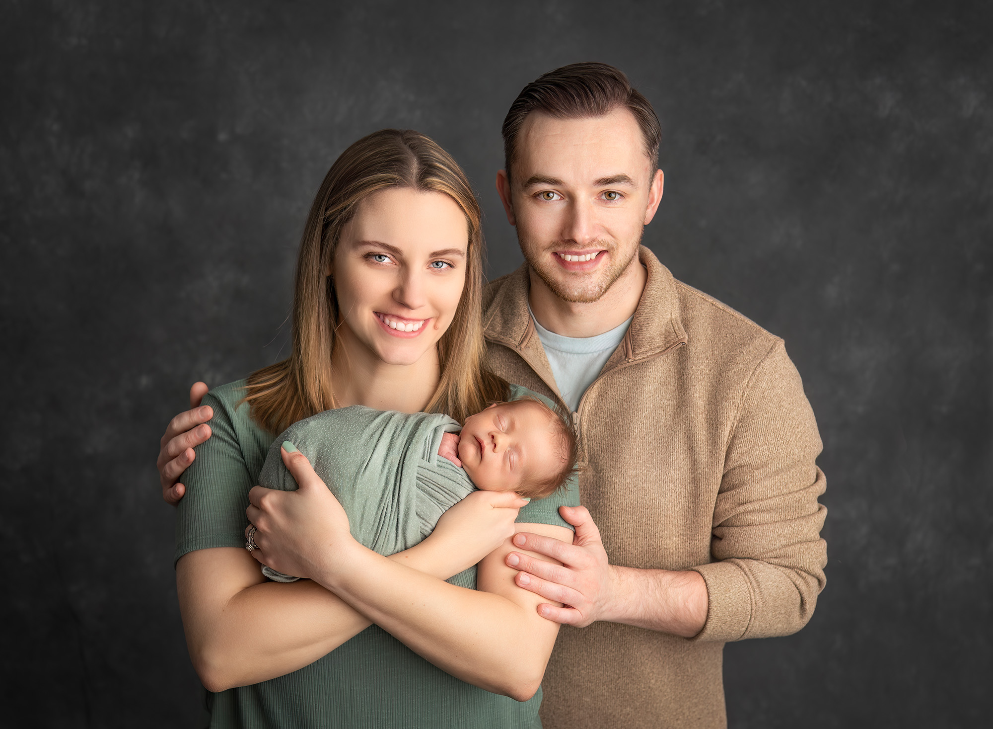 couple smiling while cradling their newborn baby boy