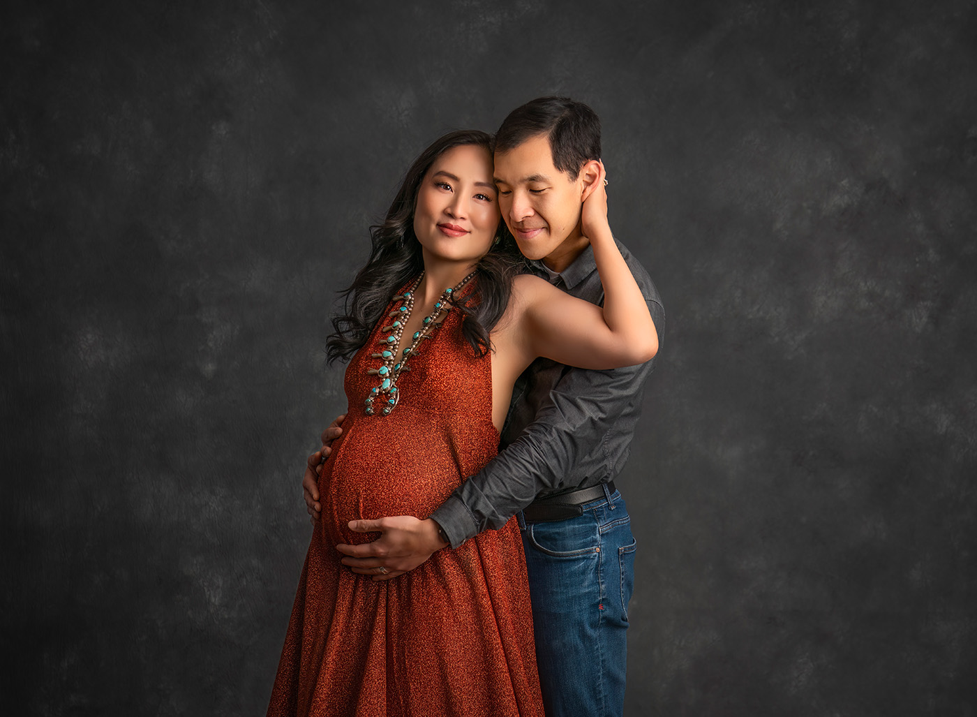 Luxury Maternity Photography beautiful Asian couple with pregnant mom and dad in loving embrace with beautiful squash blossom necklace