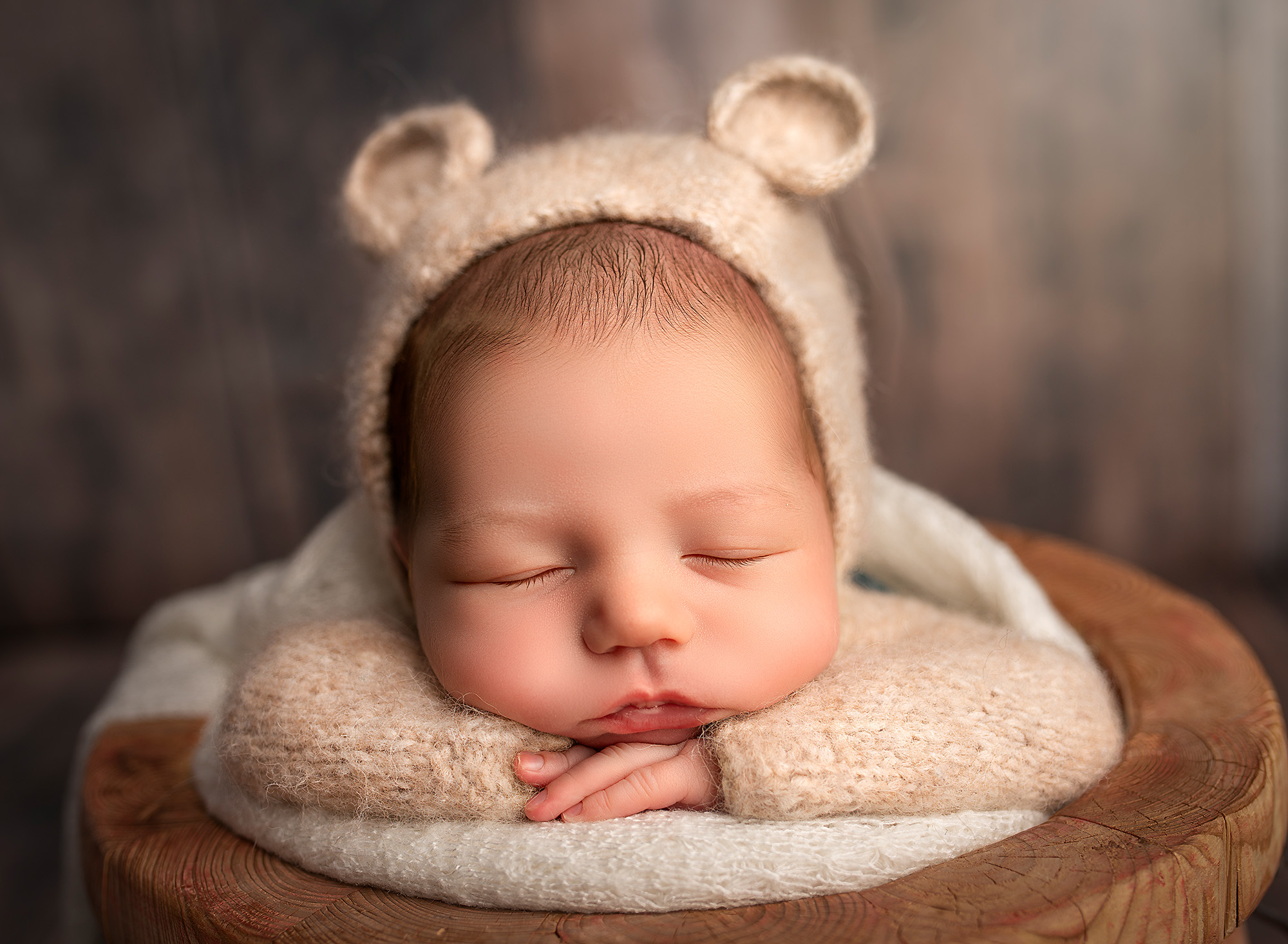 best time to take newborn photos baby dressed as teddy bear head on hands
