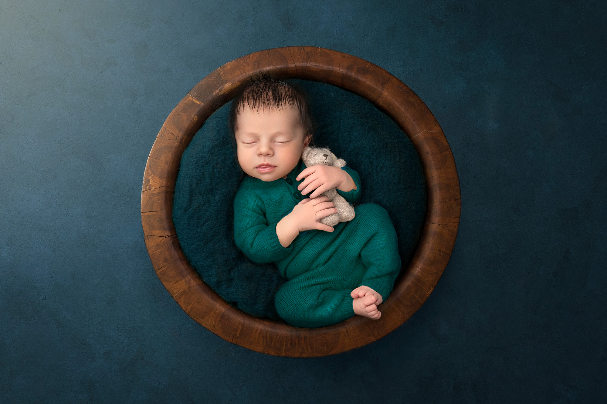 High-End Newborn Photography Connecticut tiny newborn boy holding a tiny teddy bear in a wooden bowl