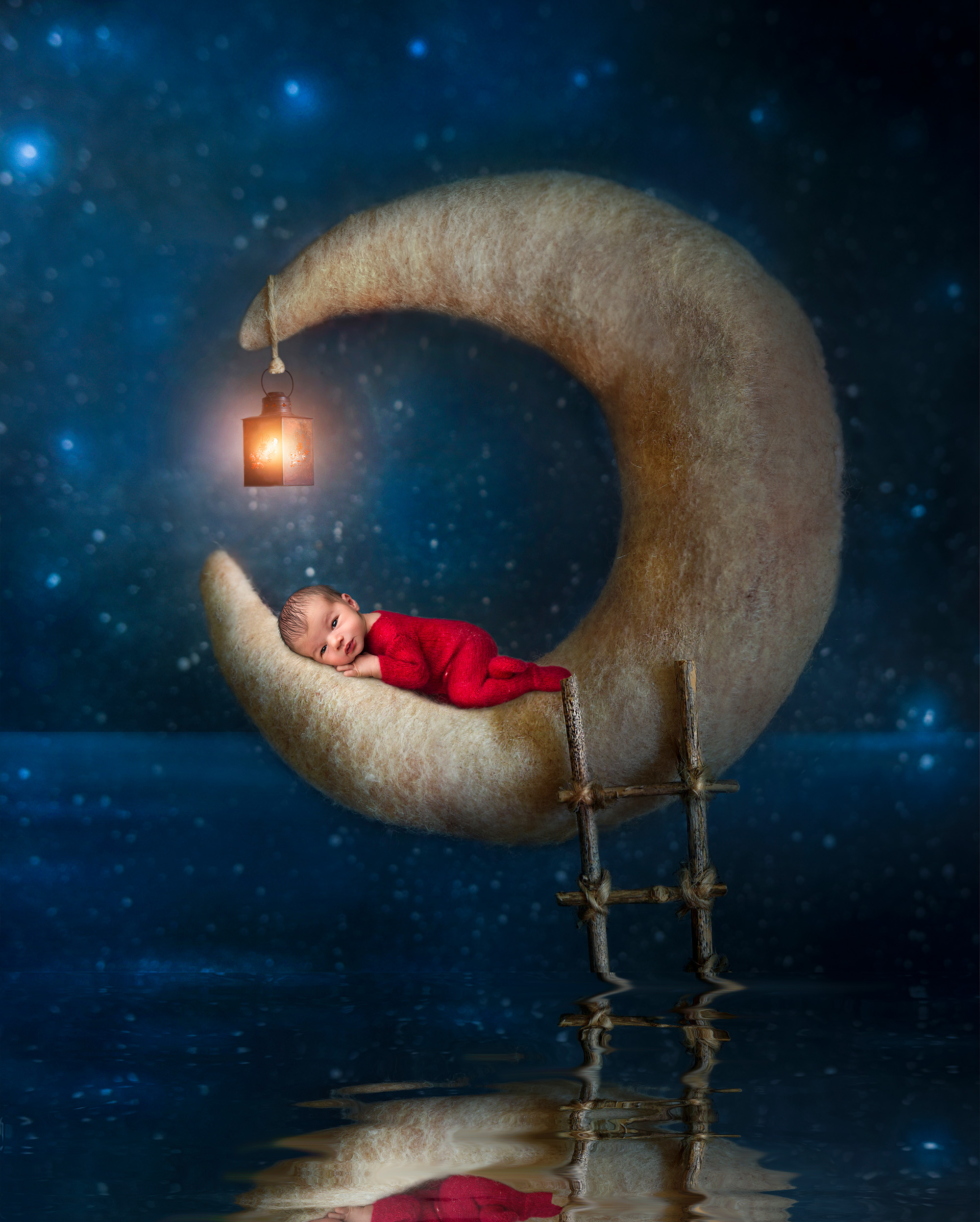 awake newborn boy resting on the edge of a crescent moon