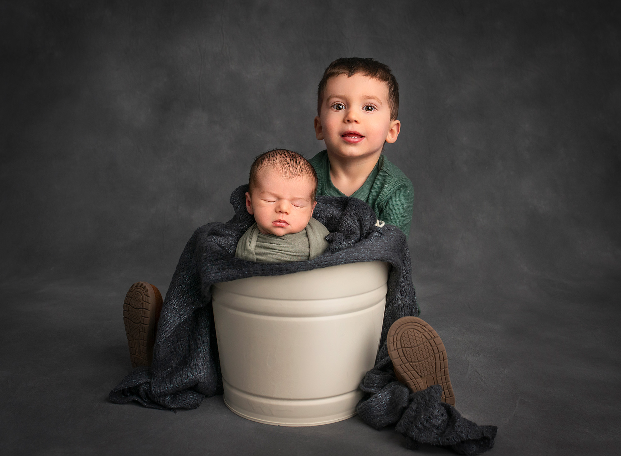 Newborn Brother newborn baby boy sleeping in a bucket with his 2 year old brother behind him