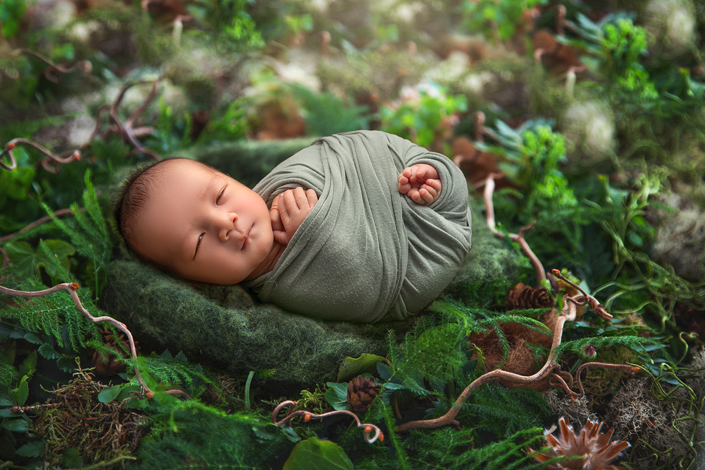 vibrant newborn photos newborn baby swaddled in green sleeping in a jungle nest