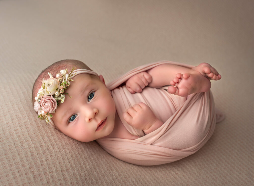 best time to do a newborn photoshoot baby girl wrapped in pink awake