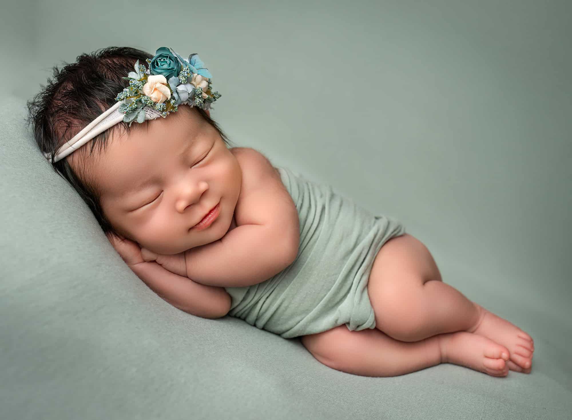 newborn photographer CT newborn baby sleeping on her side on a green background