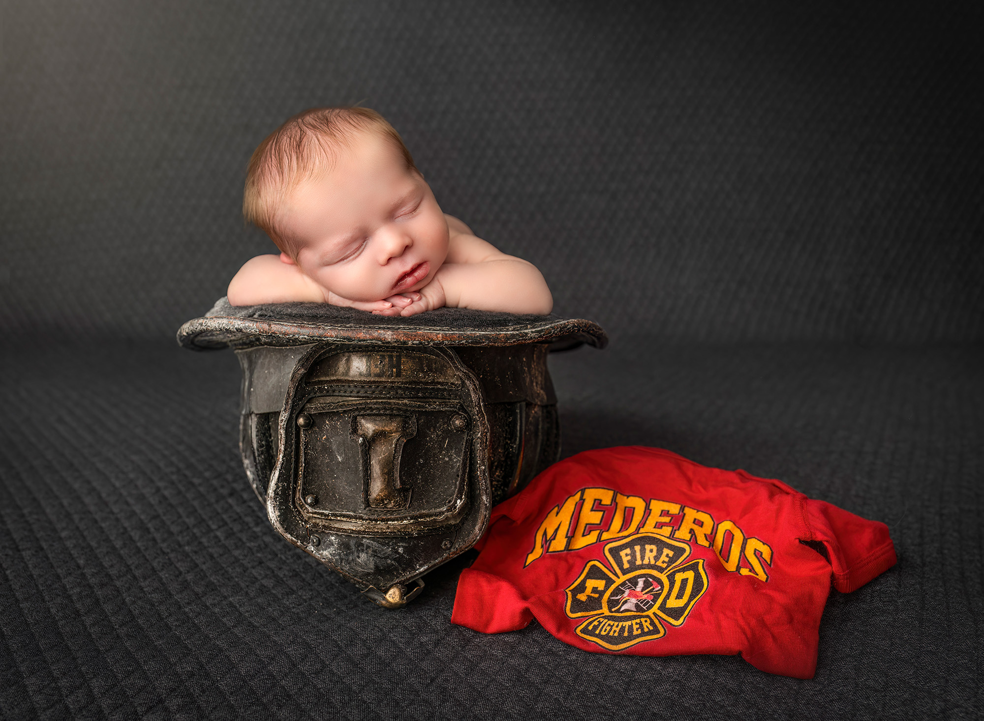 Unique Newborn Photography with Parents Newborn boy asleep in firefighter hat next to uniform with last name