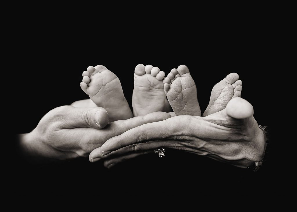 mom and dad's hands holding 2 babies feet black & white