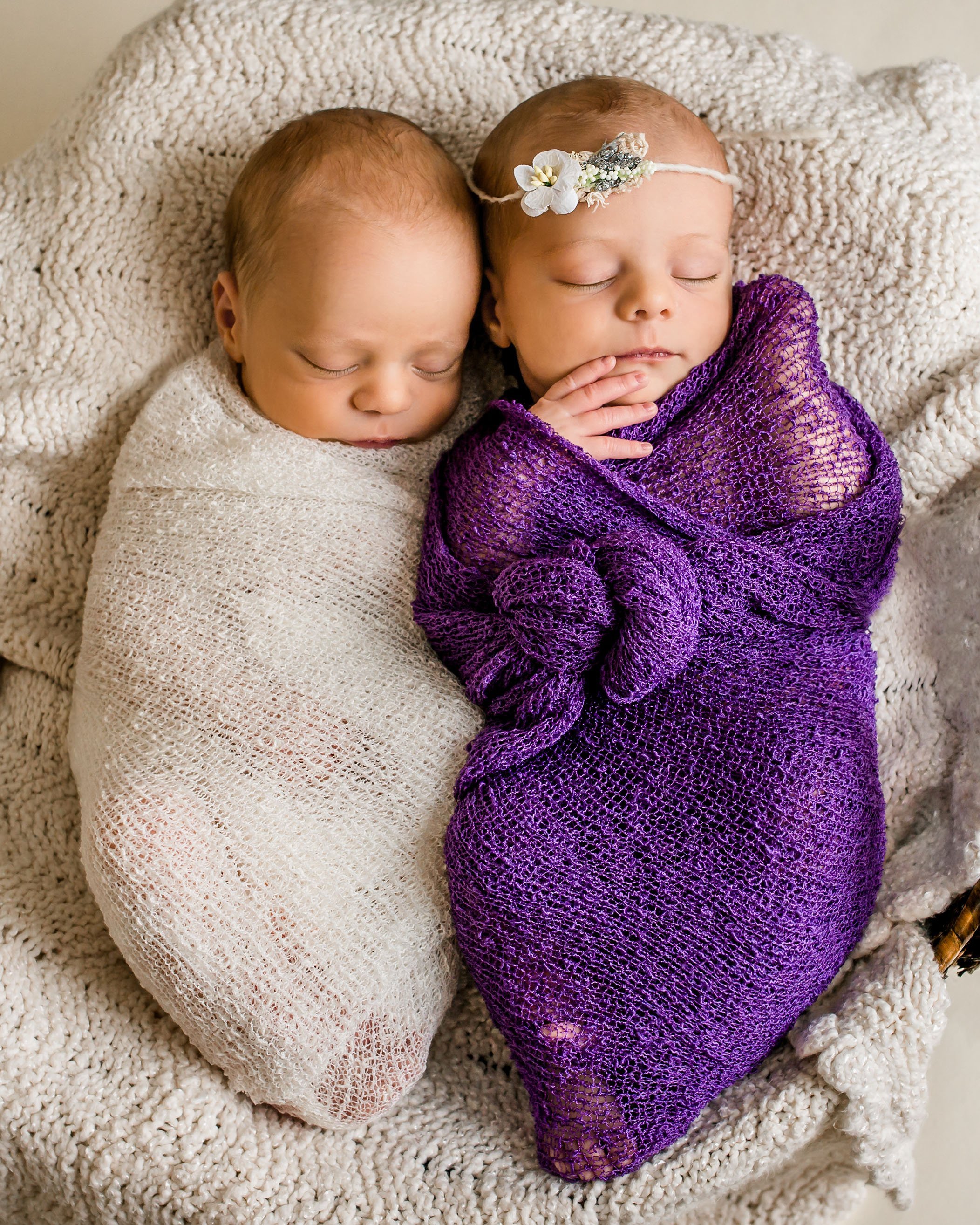 newborn twin girl wrapped in purple and newborn twin boy wrapped in cream