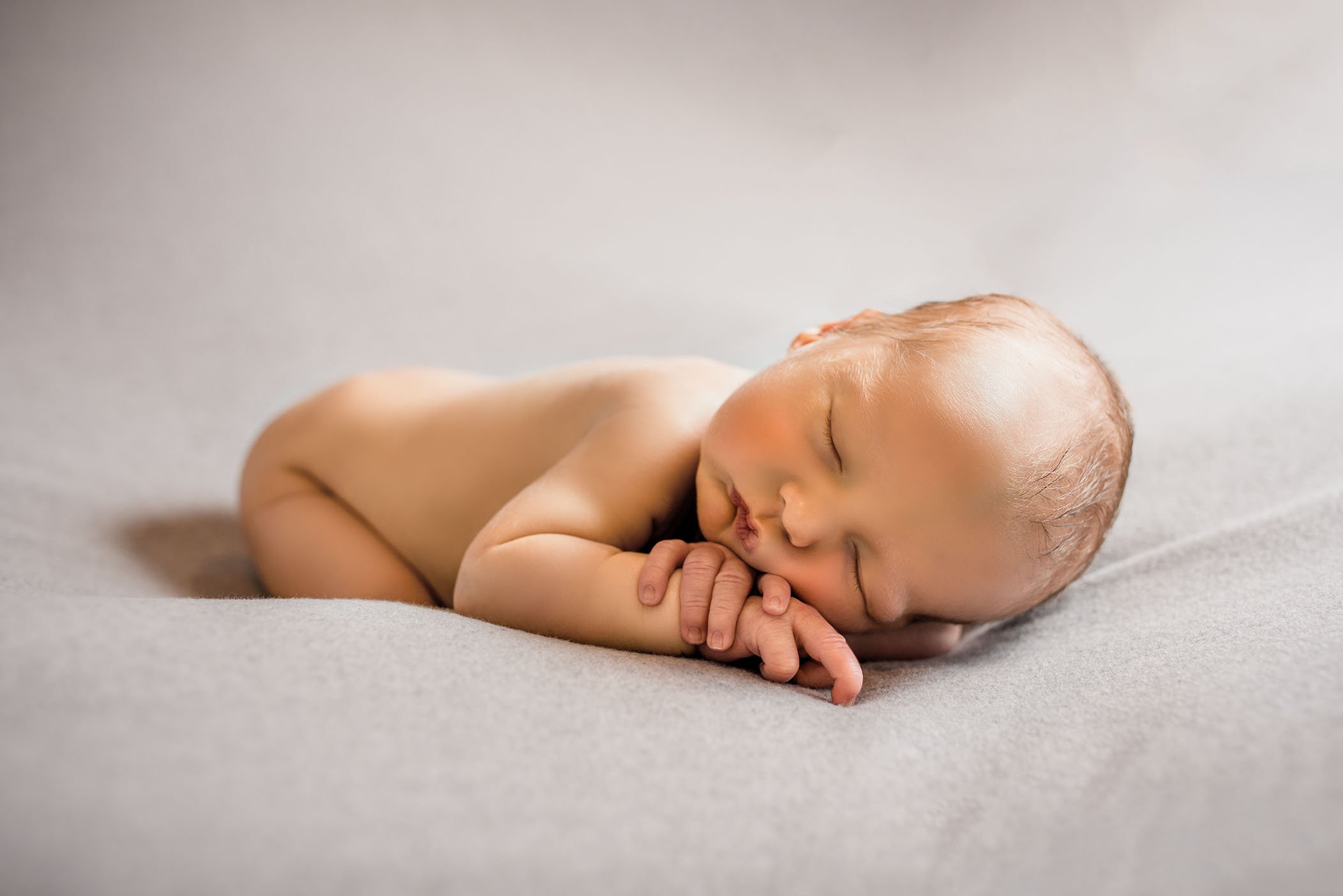 baby lying on grey background backlit and sleeping