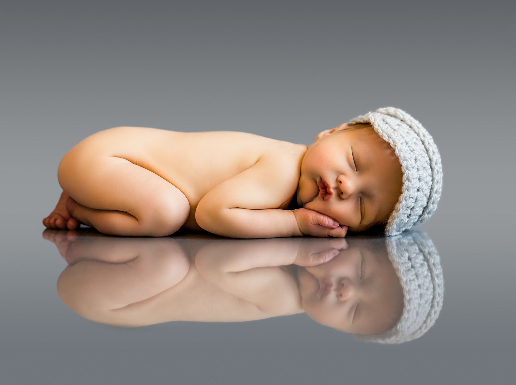 Newborn baby reflection on grey background