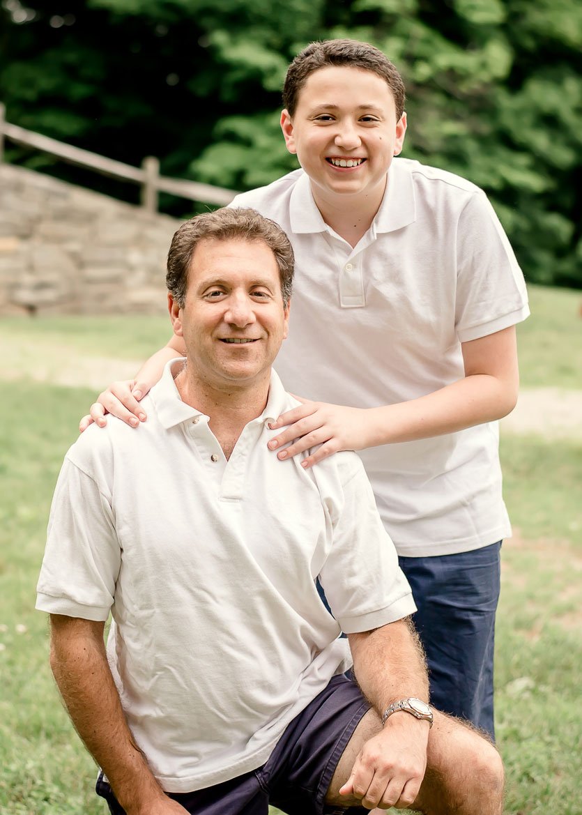 Dad and young son posed in white shirts outside in summer