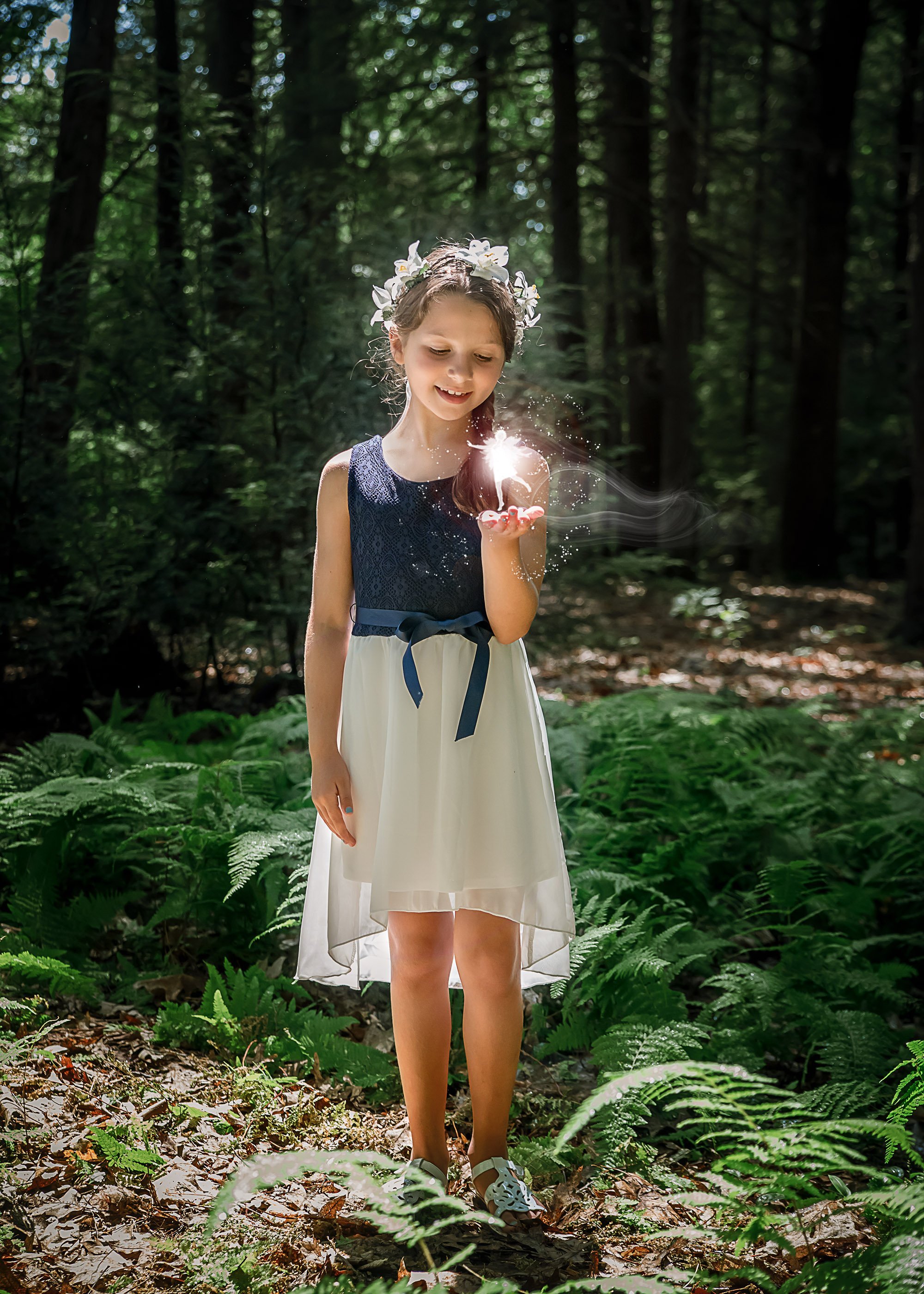 Little girl holding a light fairy in the woods