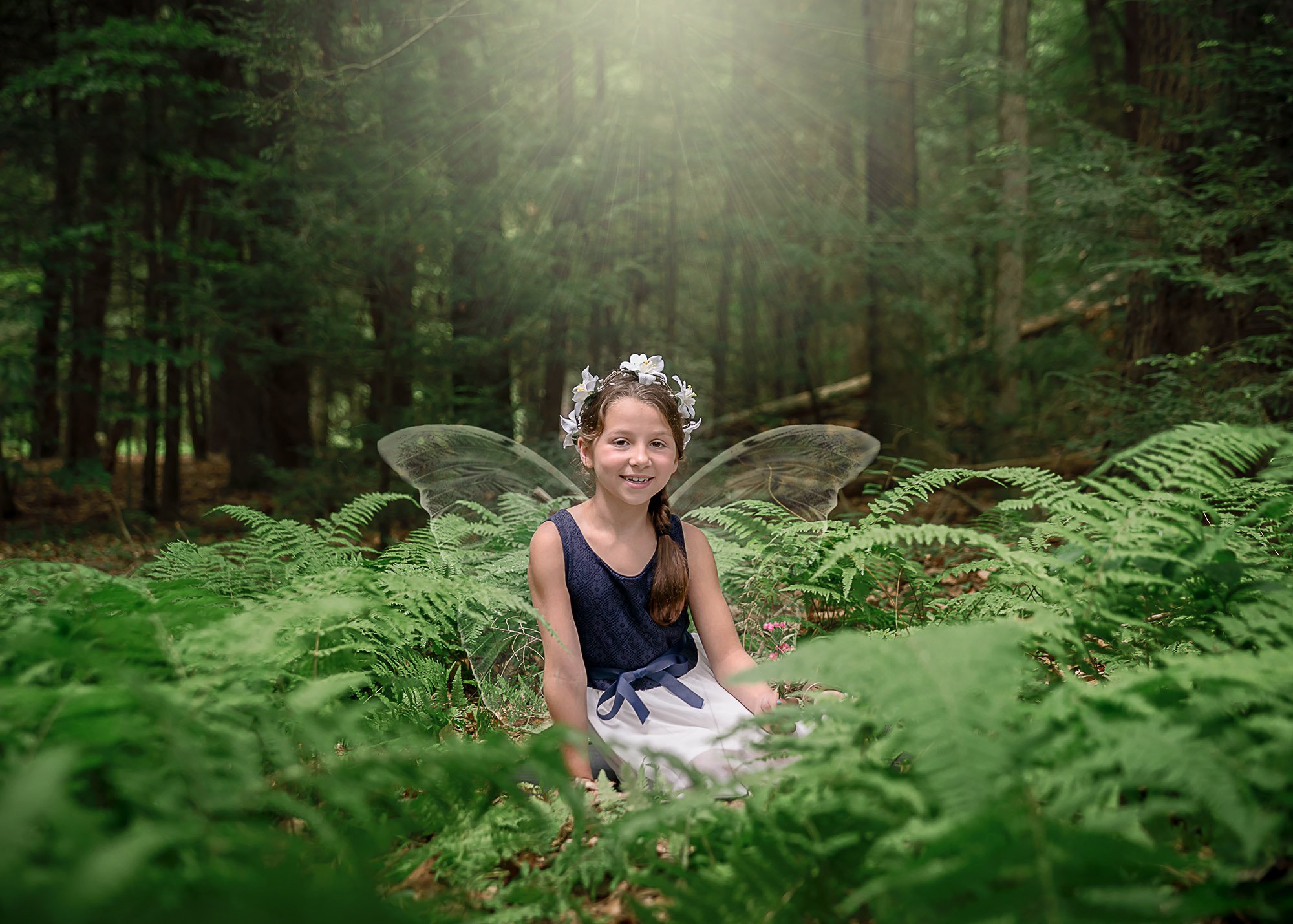 little girl fairy sitting in the ferns in the woods