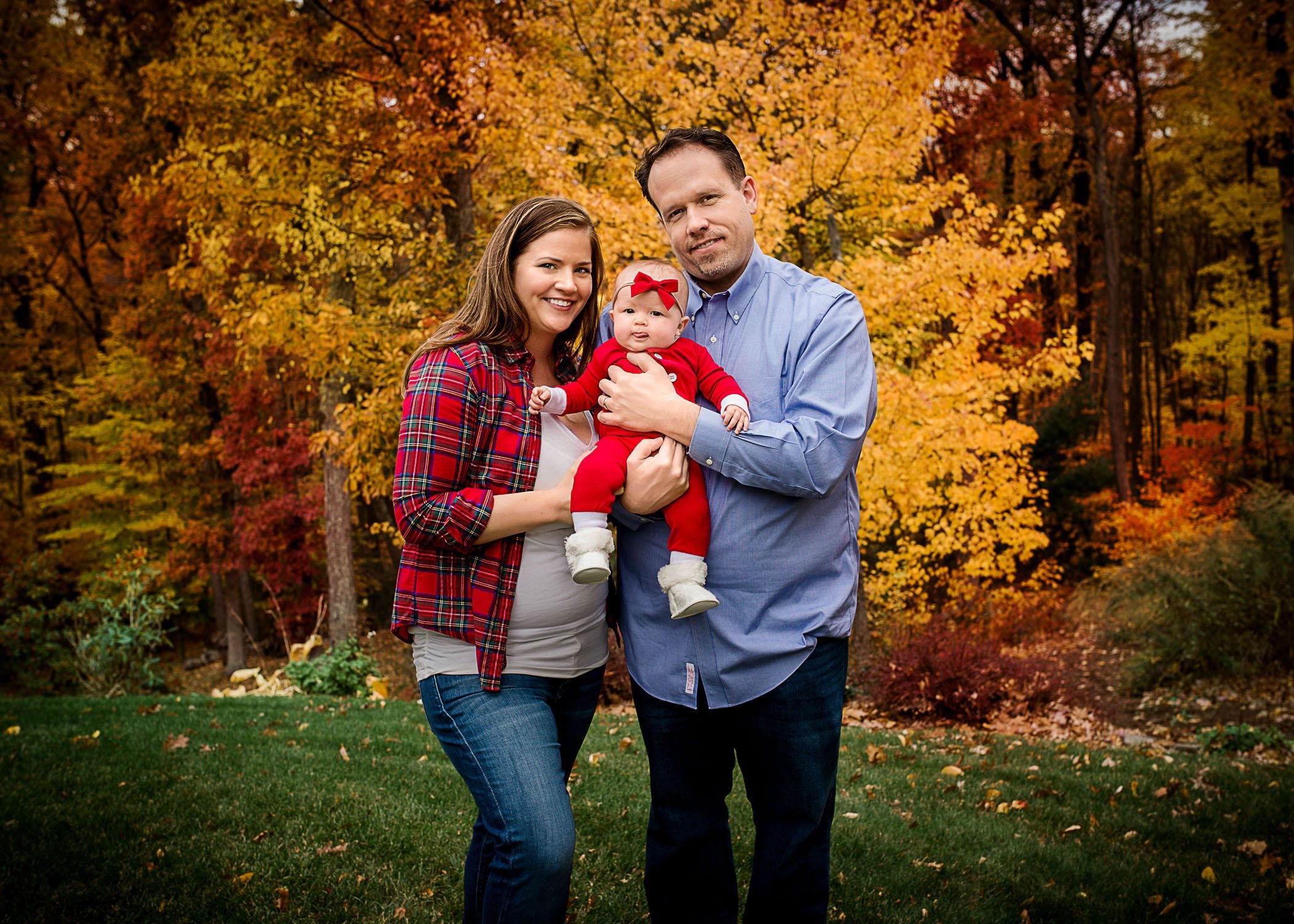 Mom and Dad hold 6 mo old baby girl outside with fall foliage One Big Happy Photo